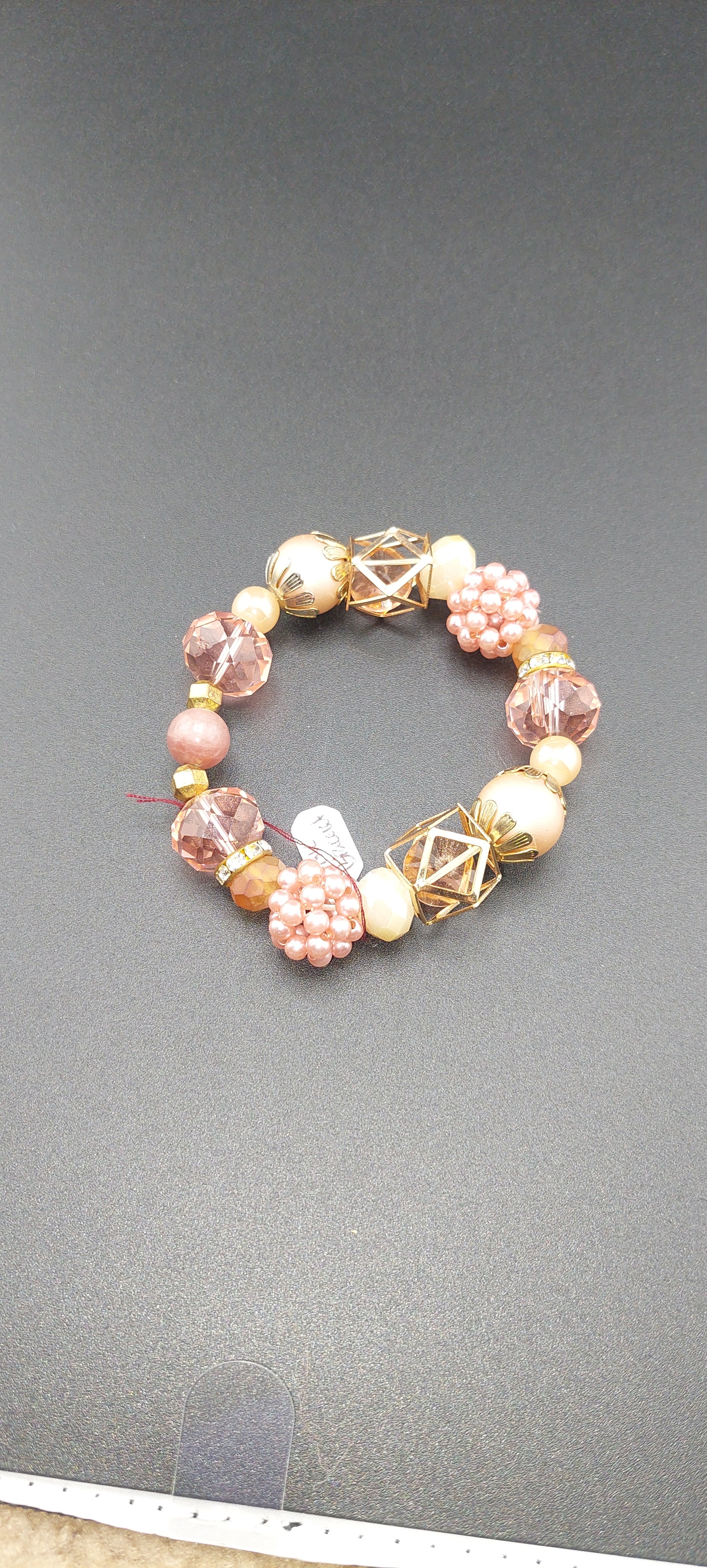 A two-tone pink bracelet with geometric patterns and a glossy finish on a flat surface.