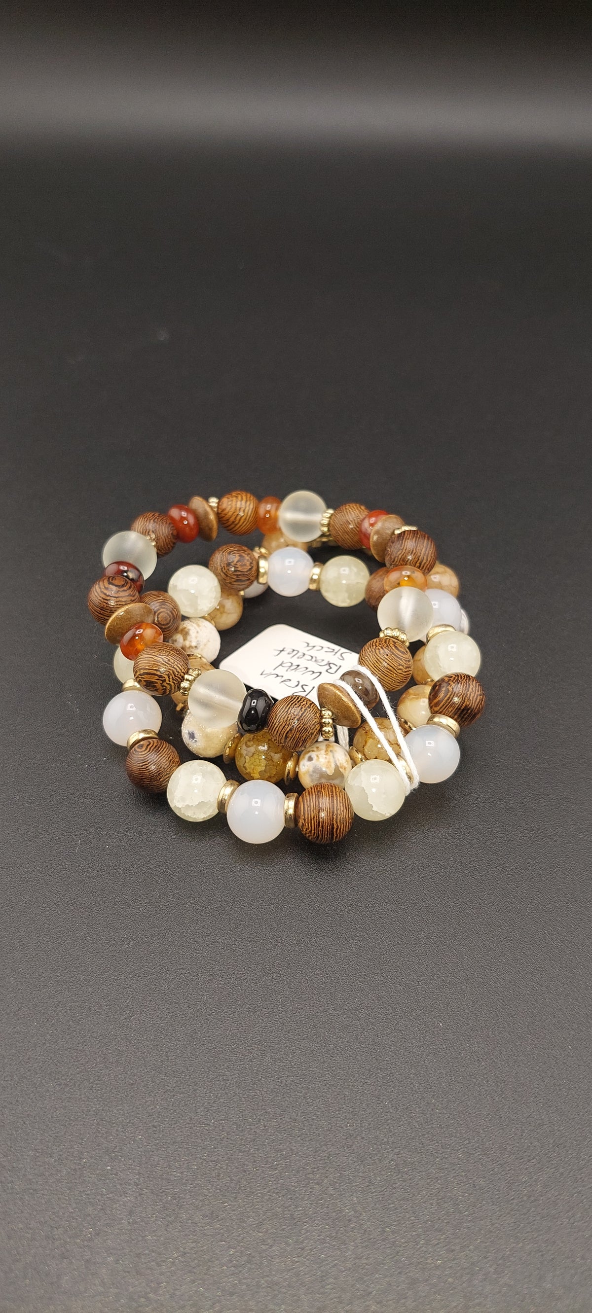 A triple stack bracelet with a combination of metallic and bead elements, displayed against a dark background.