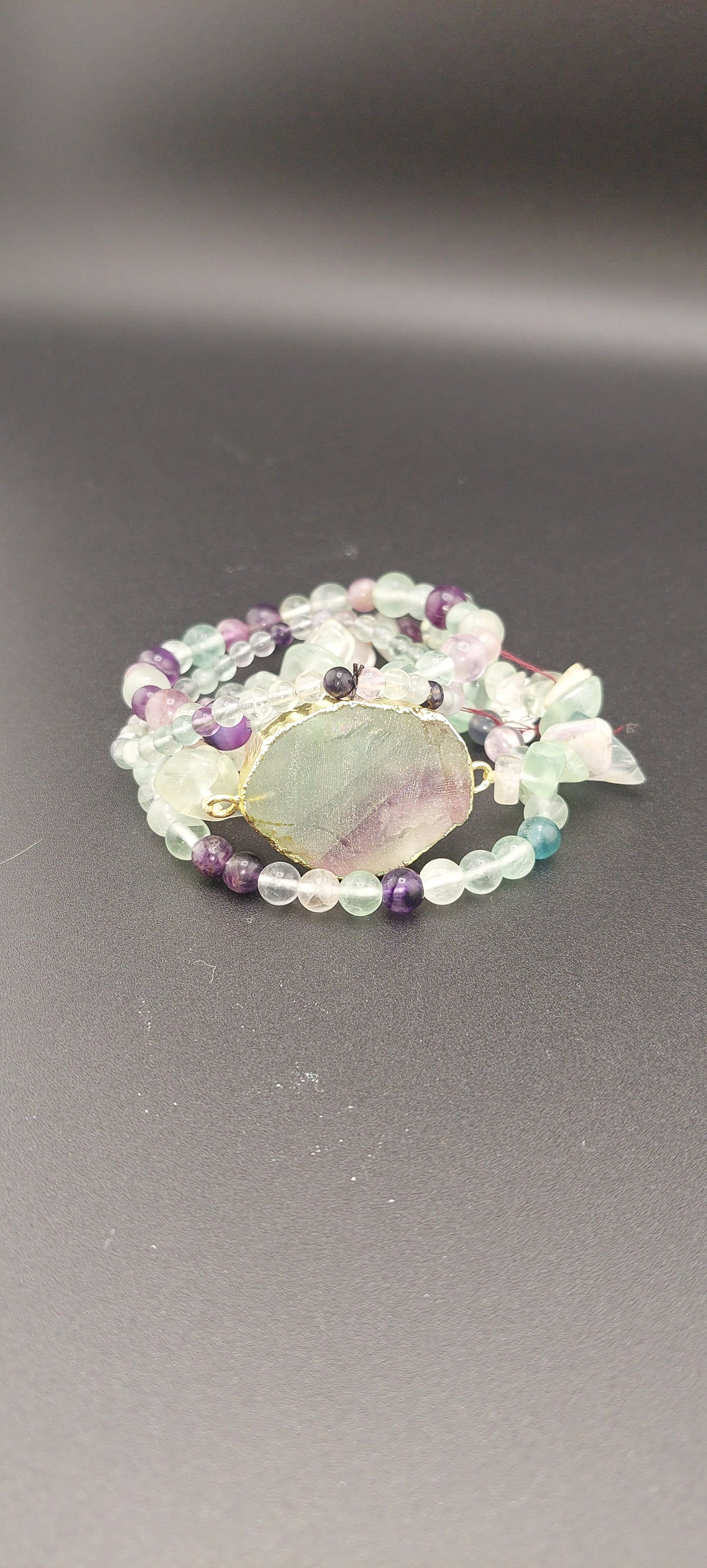 A stack of round fluorite beads in various shades of purple, green, and translucent, tied with a ribbon.
