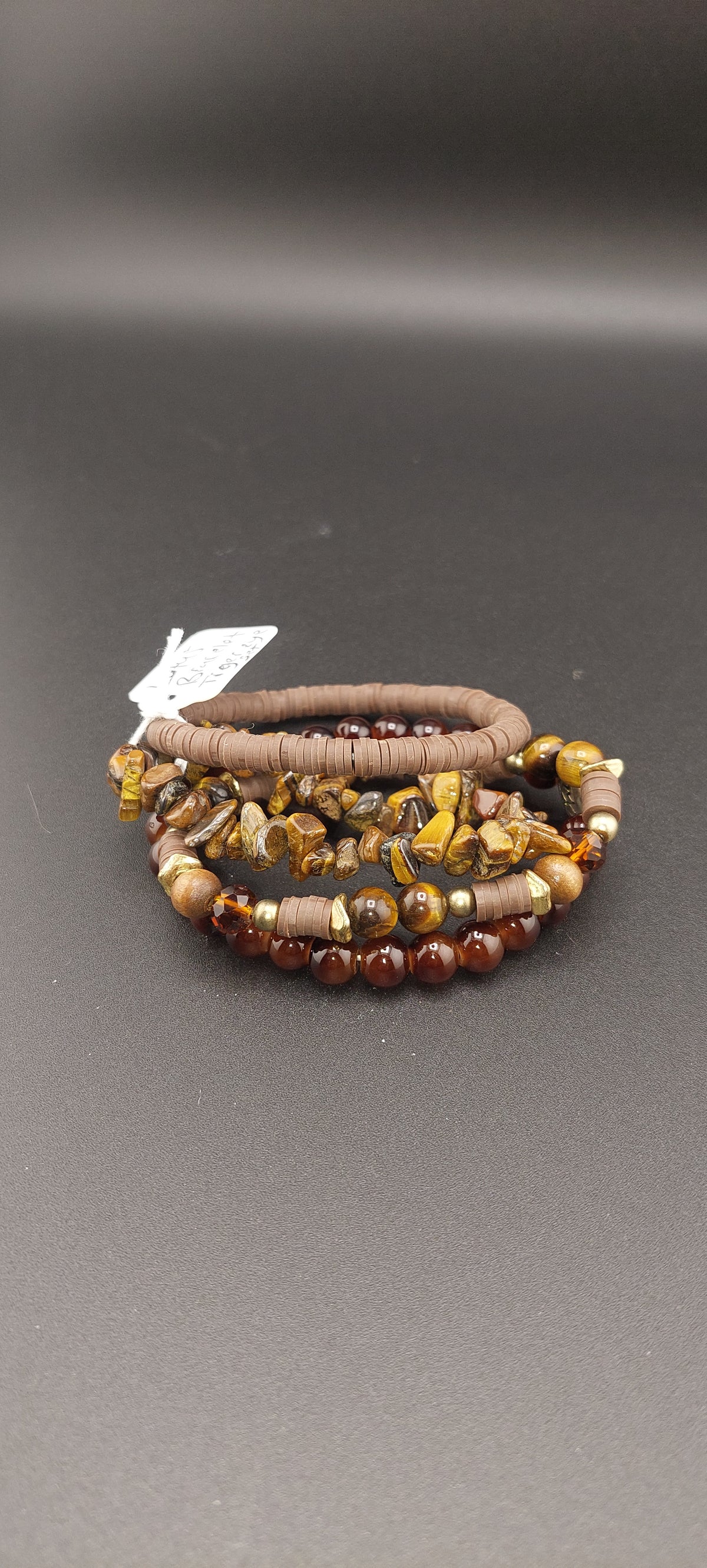 A stack of bracelets made with Tiger's Eye stones, featuring a combination of brown, black, and yellow colors.