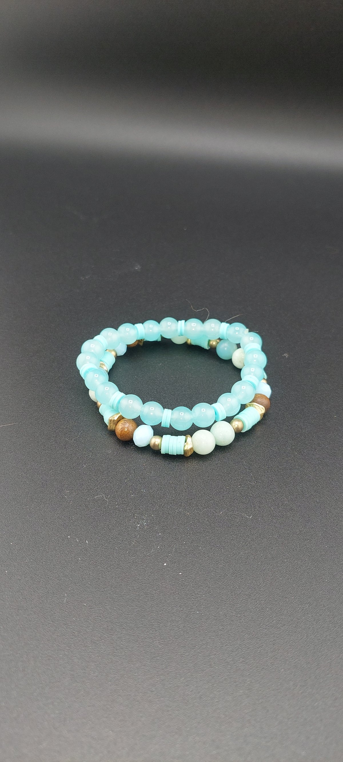 A two-layered blue bracelet with bead-like elements on a dark background, presented as a fashion accessory.