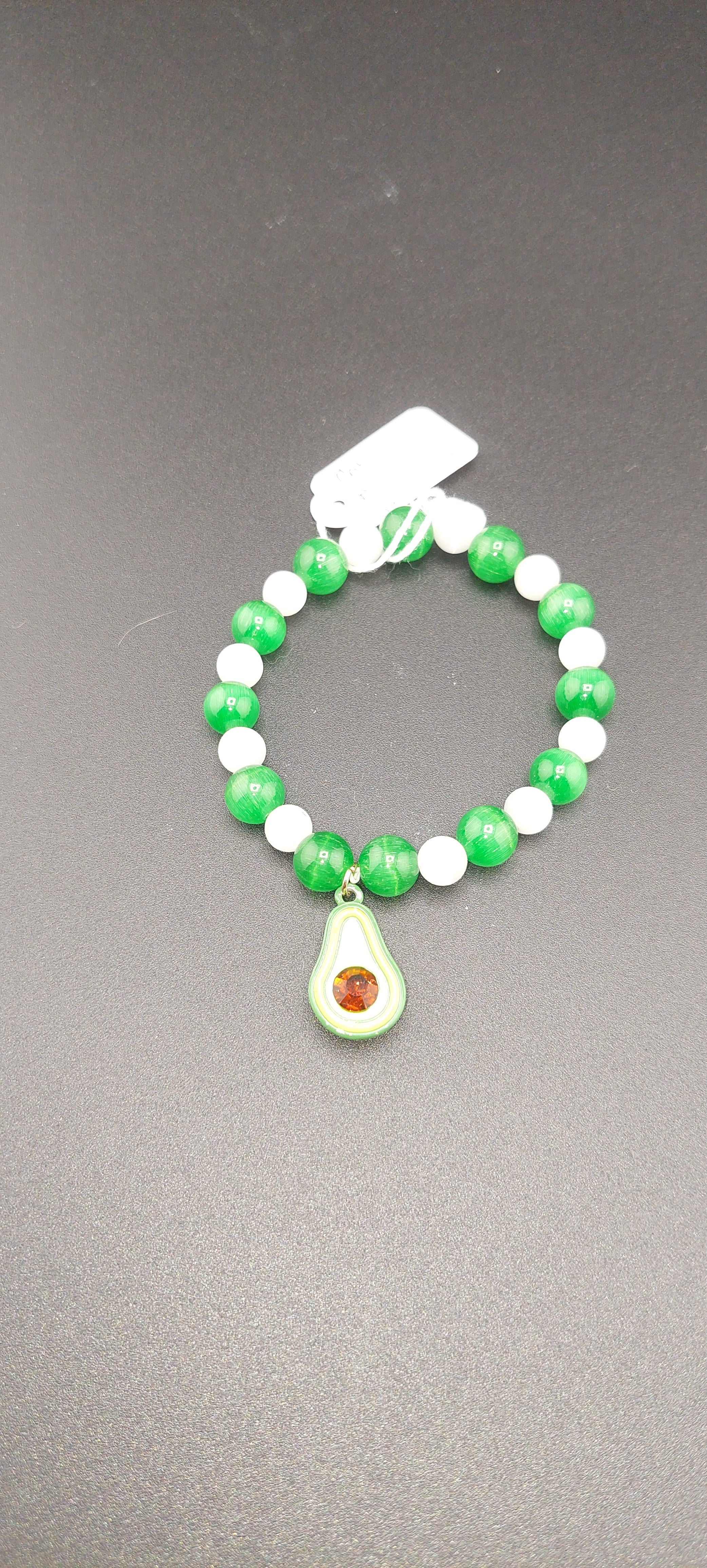 A bracelet with green and white beads, featuring an avocado charm.