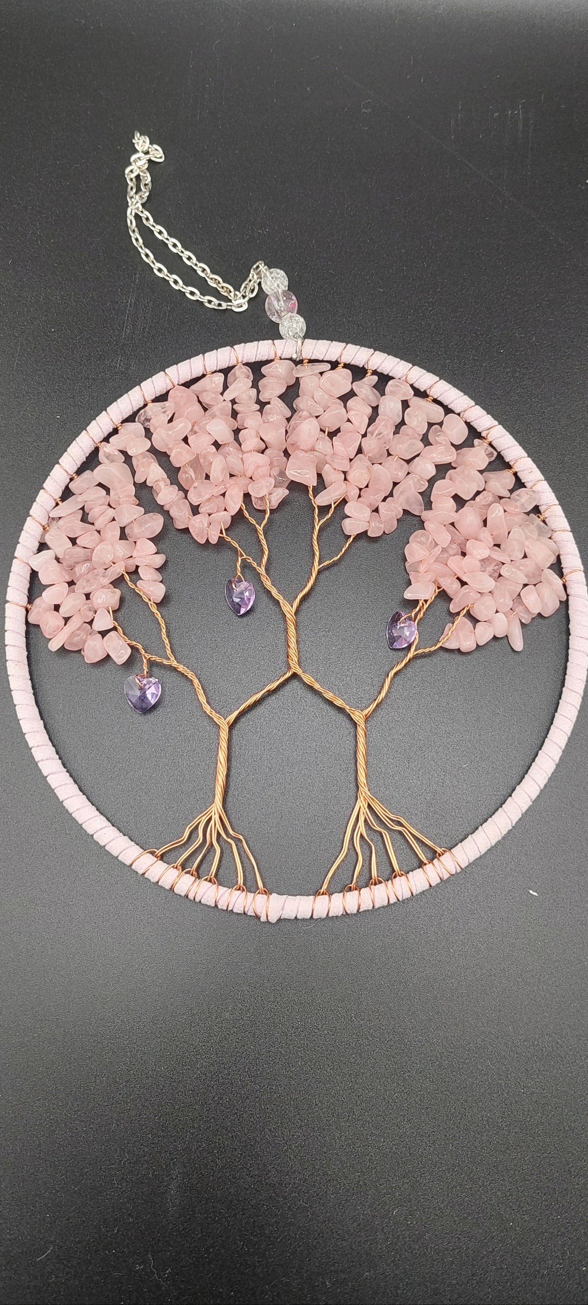 Decorative wall hanging with a tree design on a dark background made with rose quartz crystal chip beads.