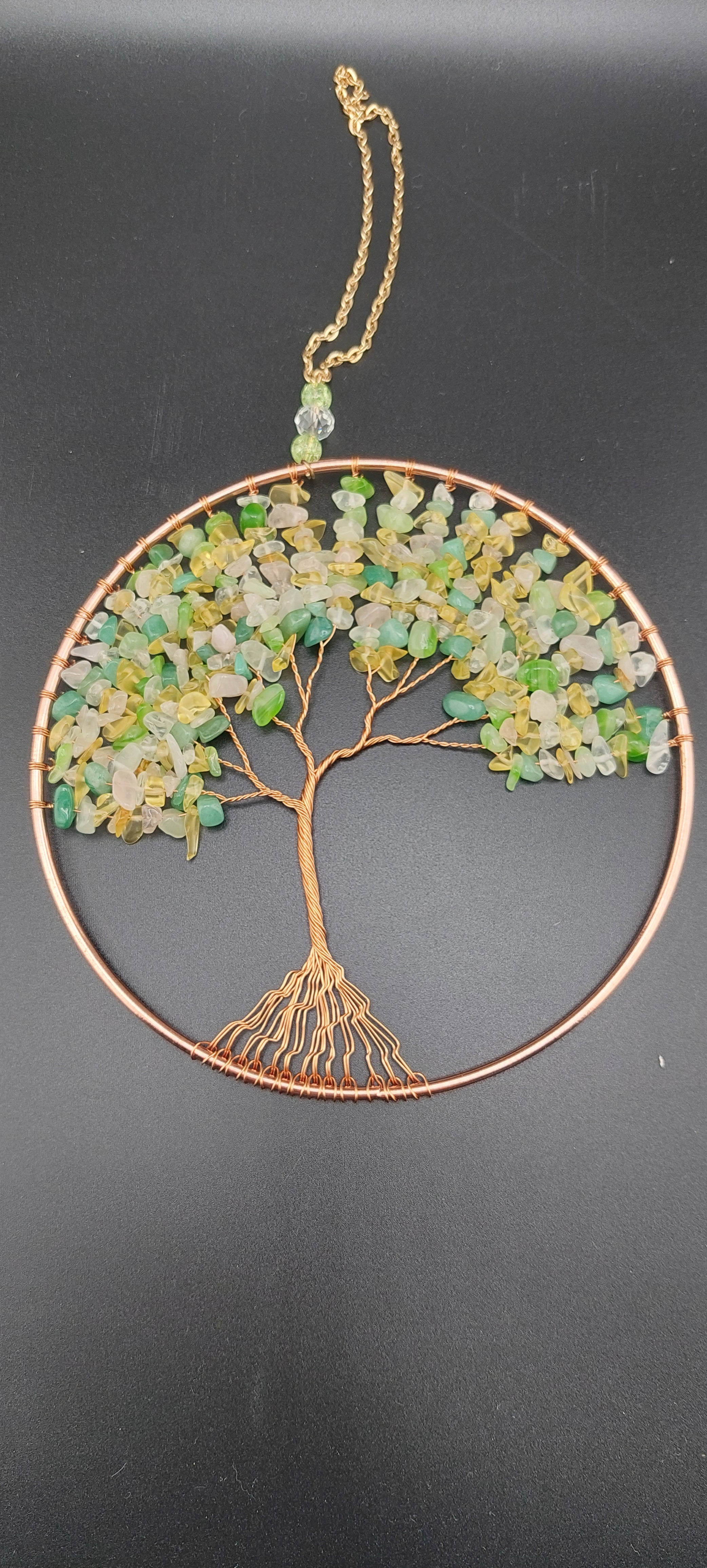 A dream catcher featuring a tree of life design, with green and citrine stones, and non-tarnish wire.