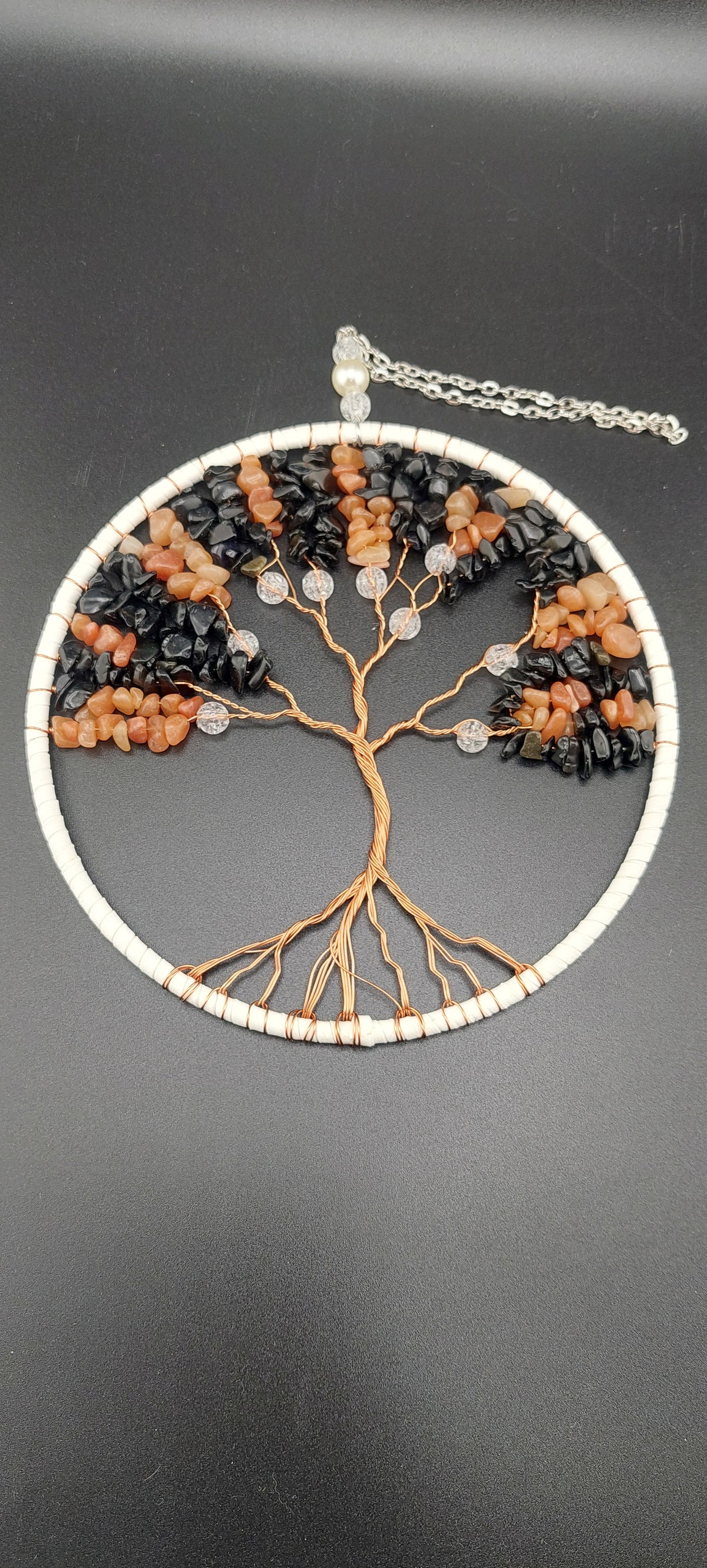 A hand made wire woven dream catcher featuring a tree of life design with healing crystals, predominantly in brown and white colors.