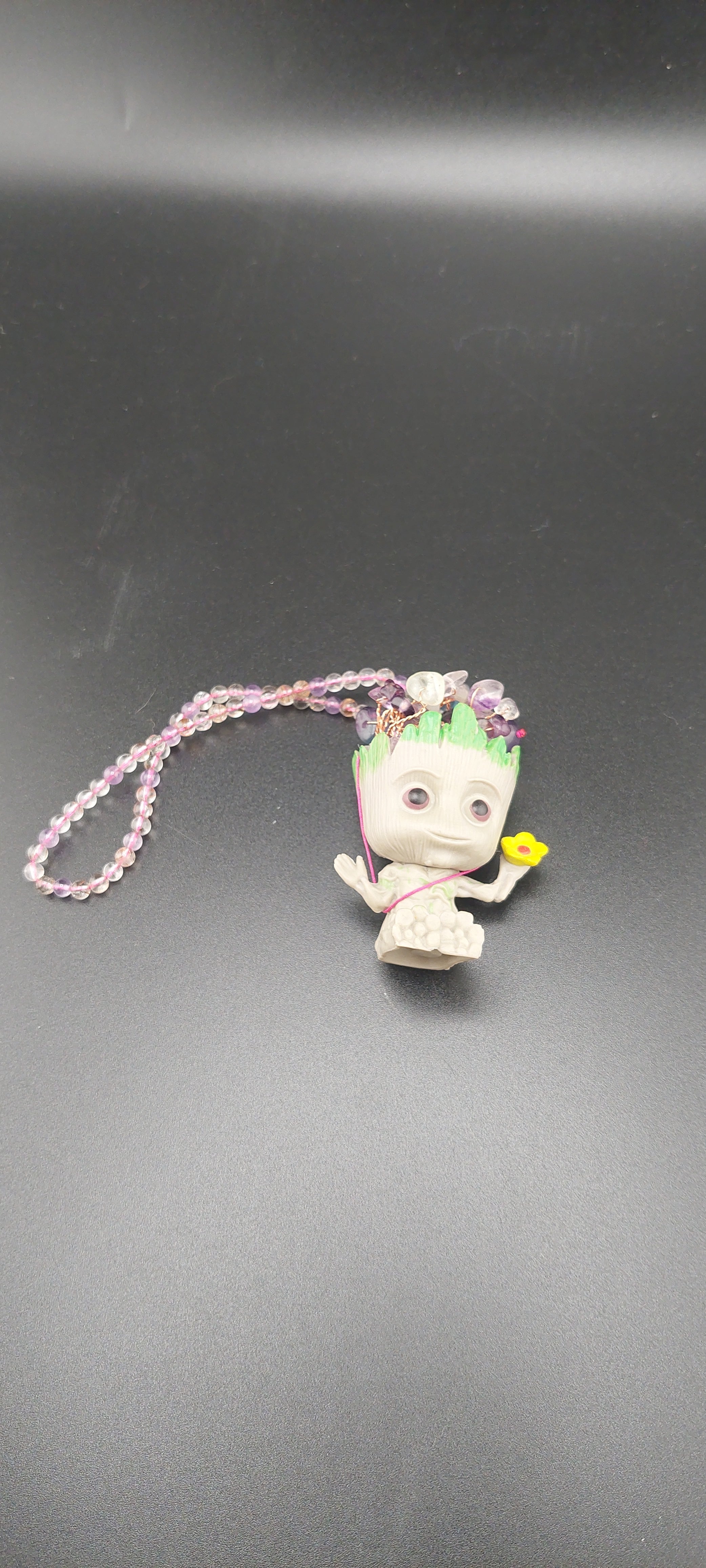 A keychain featuring an animated character Groot in multicolor attire, attached to a fluorite crystal and a super 7 stone.