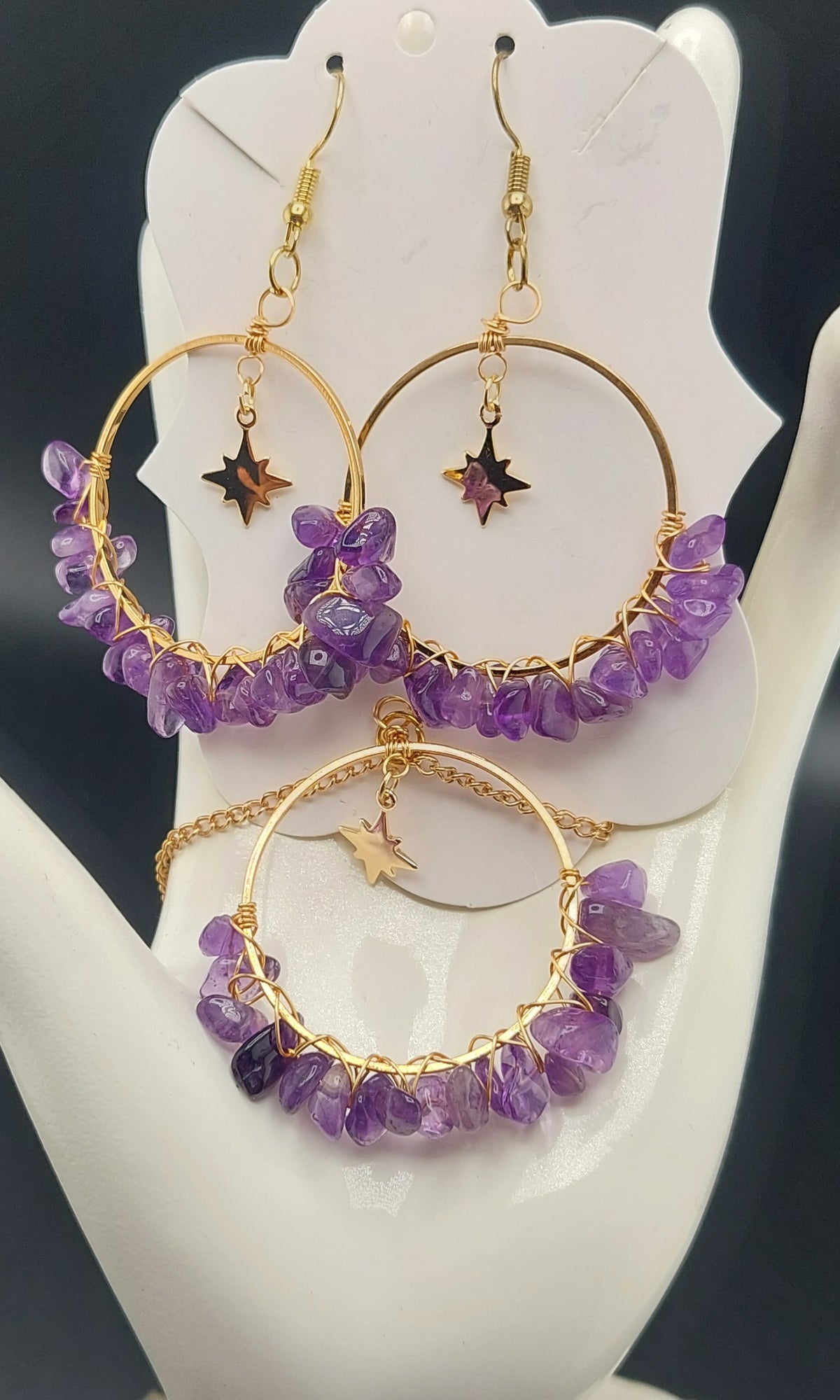 A set of hoop earrings adorned with amethyst stones and presented on a white display stand.