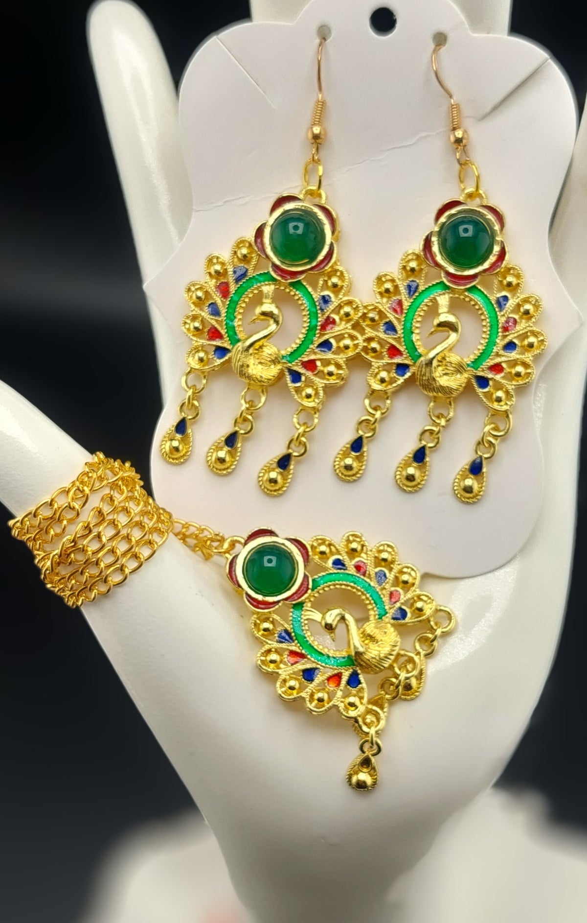 A set of gold-colored jewelry featuring a peacock design, displayed on a mannequin head.