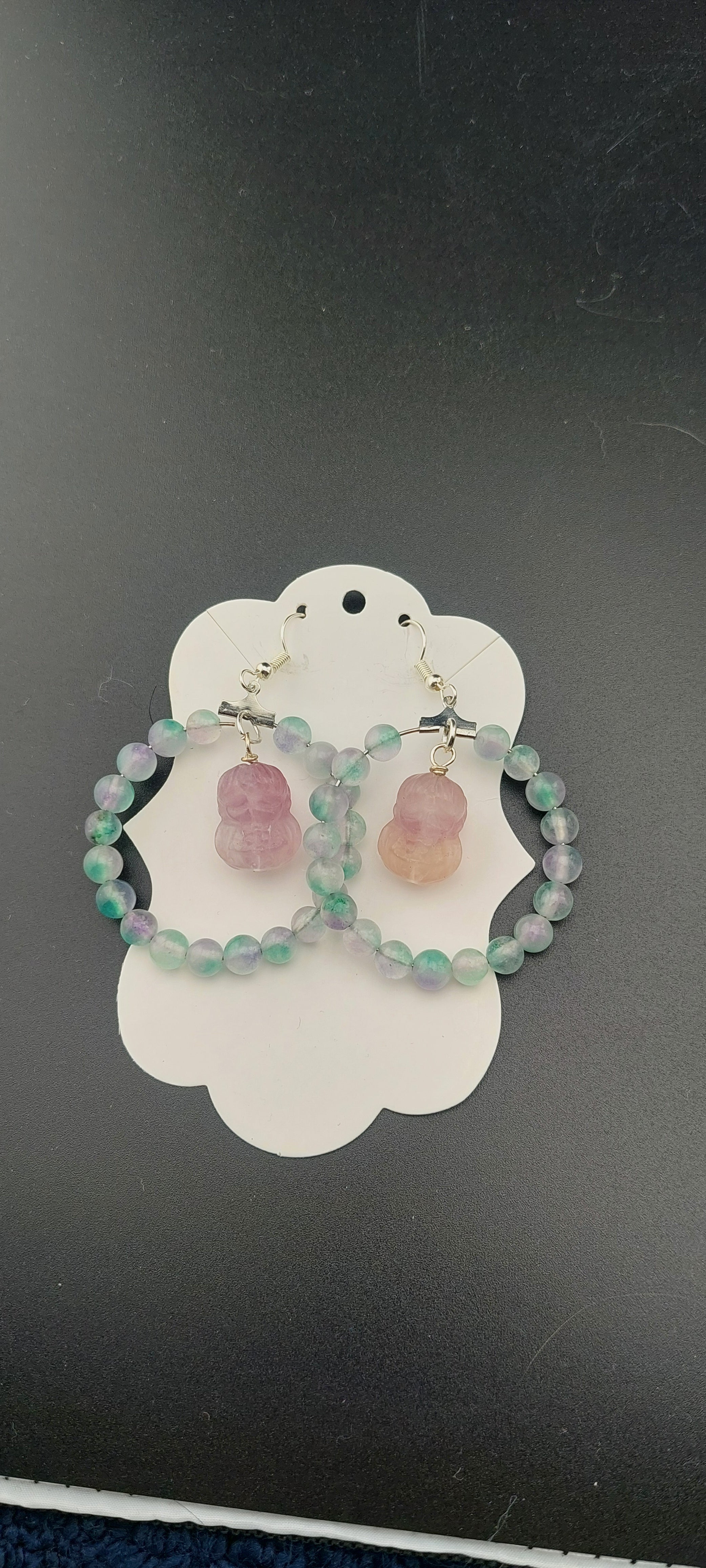 A pair of Sailor Venus hoop earrings with multicolored beads, displayed on a white card.