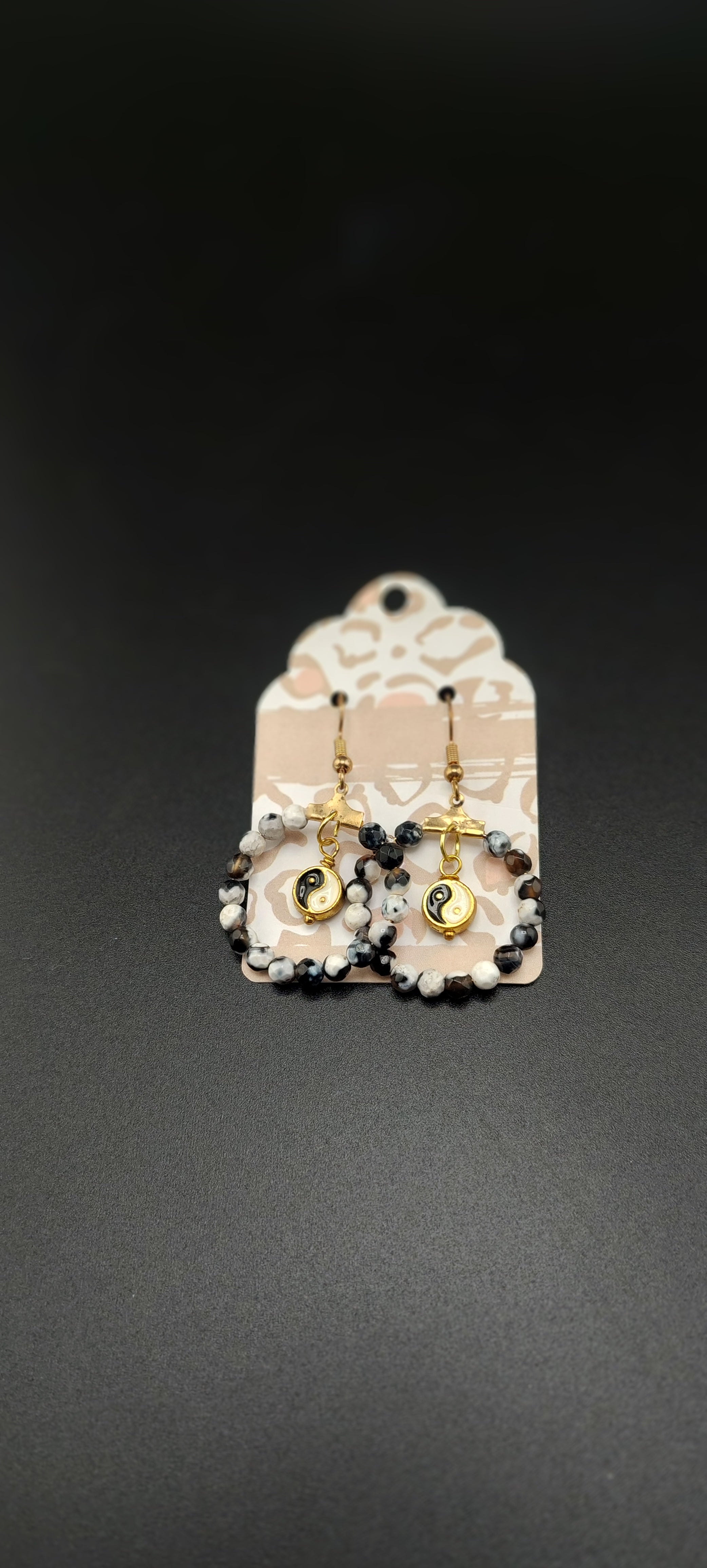 This image features a pair of elegant ying yang hoop earrings. The earrings are designed with a black and white pattern, creating a classic and timeless look.