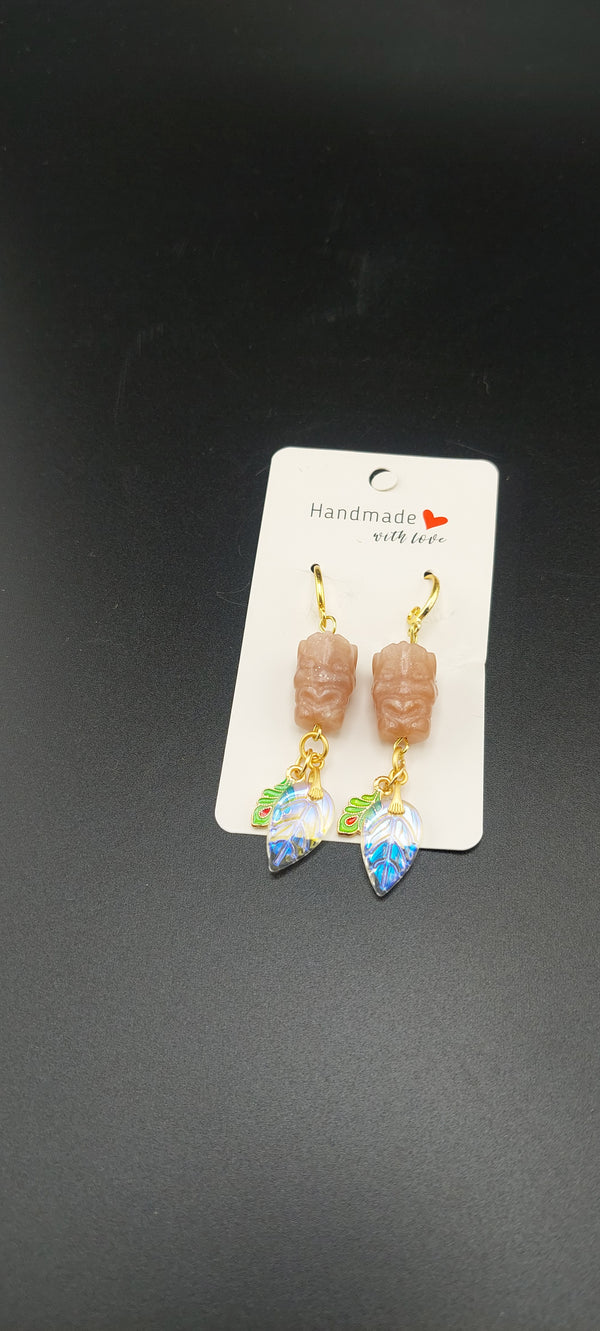 A pair of earrings featuring peach moonstone beads, displayed on a white card with a printed logo.