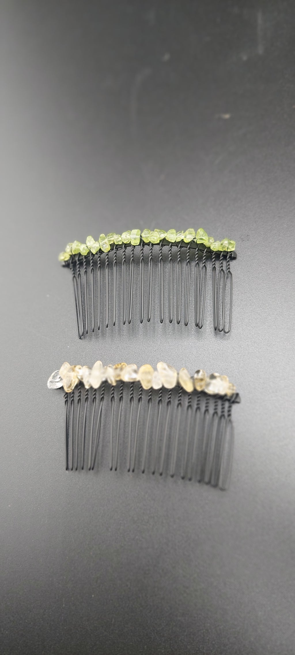 Two black hair clips with green and white accents on a dark background.