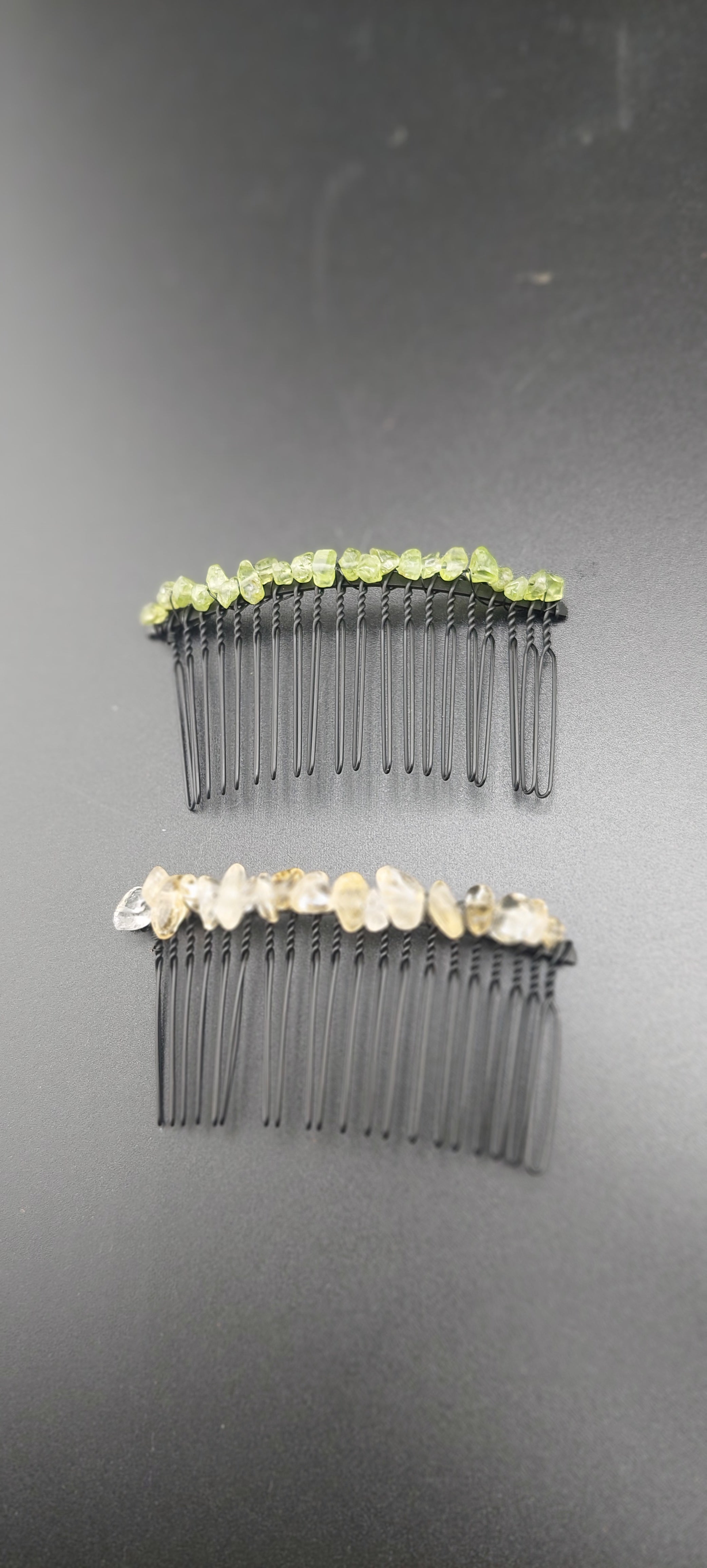 Two black hair clips with green and white accents on a dark background.