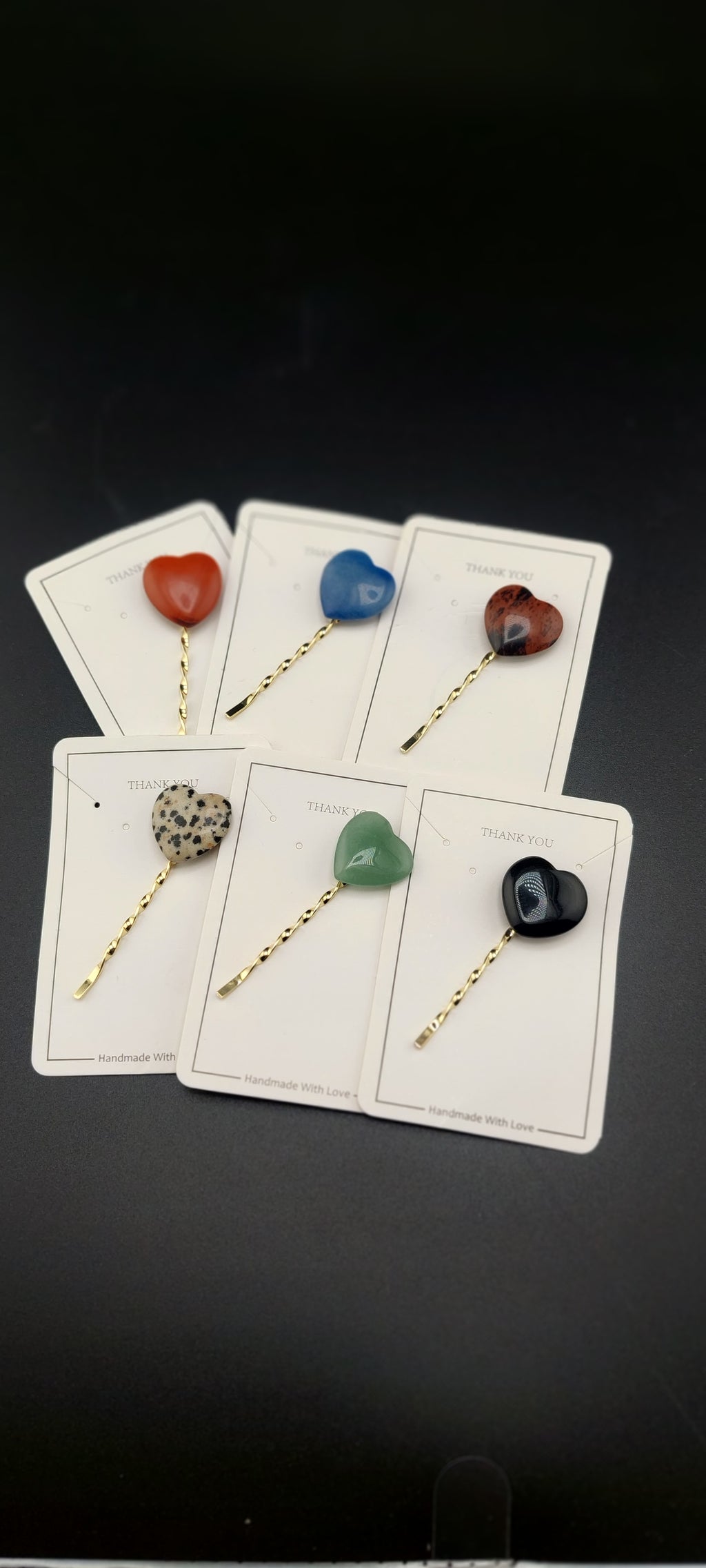 A selection of hair pins each featuring a different colorful stone attached to a gold-colored pin-prong.