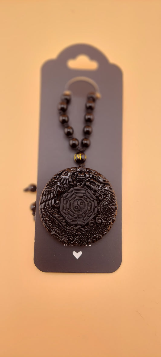 A black obsidian Yin Yang Men's necklace on a display card against a beige background.