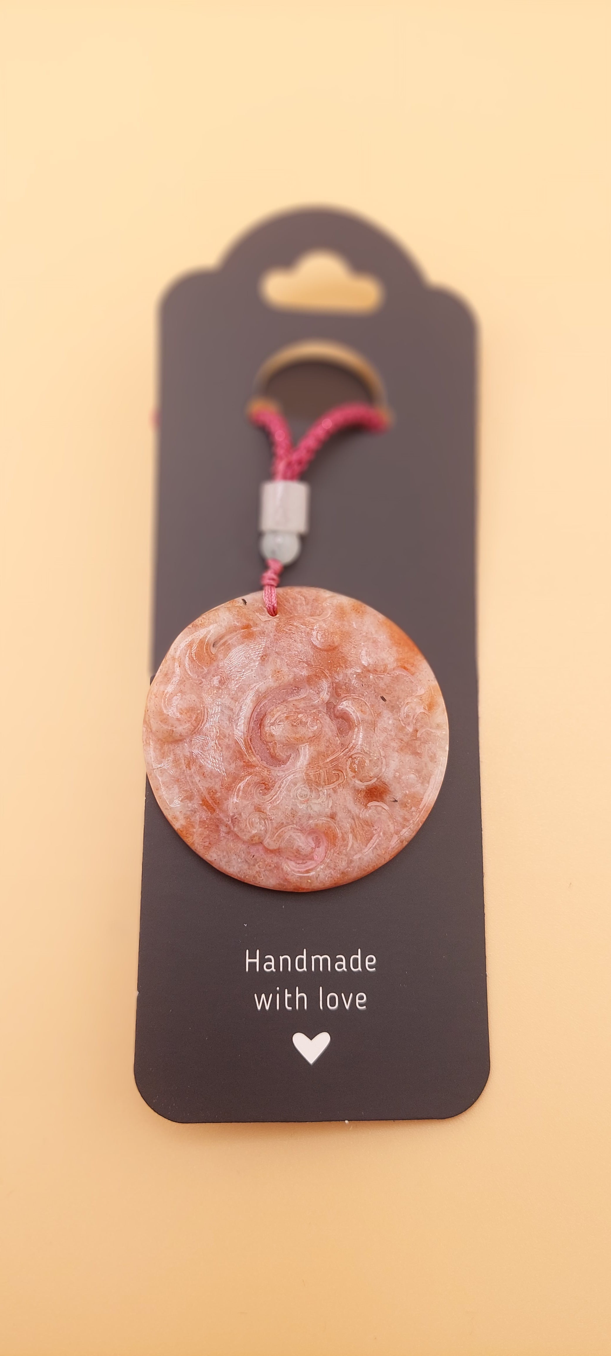 A Phoenix-themed carved necklace presented on a card with the text 'Handmade with love'.