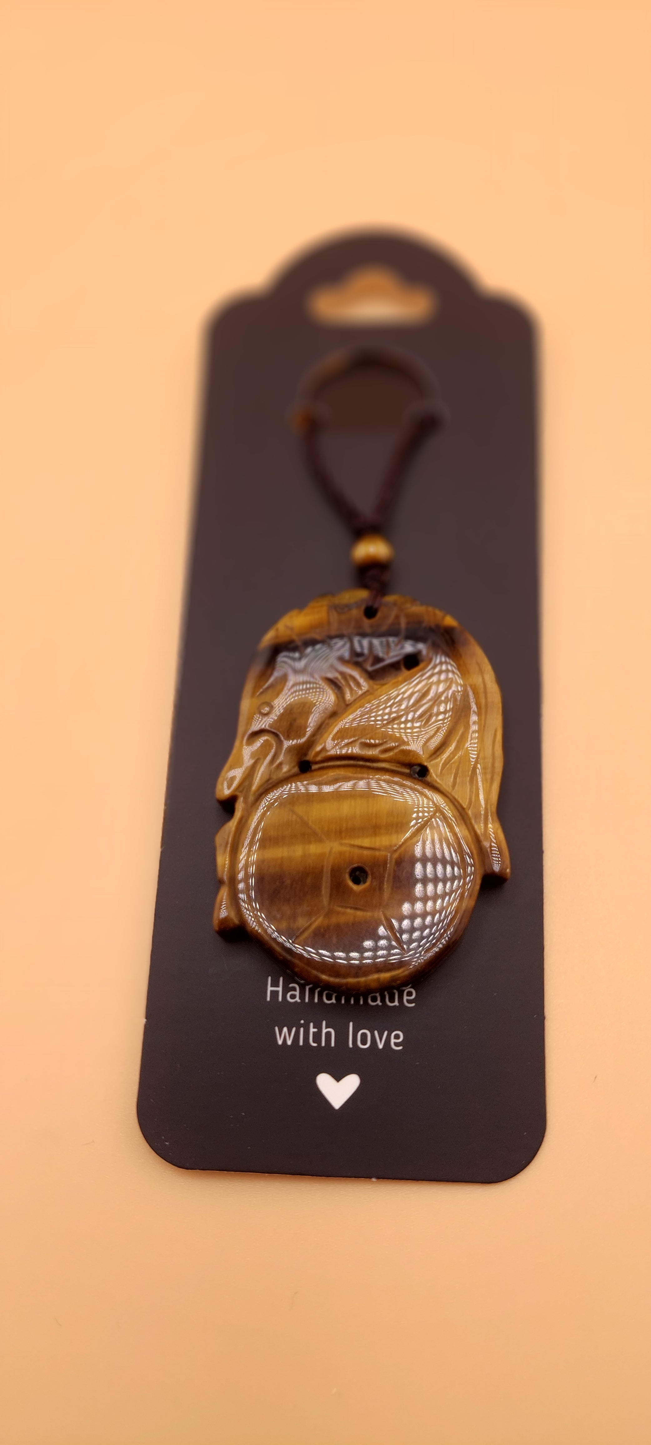 A Tigers Eye Koy Fish necklace displayed on a black card with the text 'Handmade with love'.