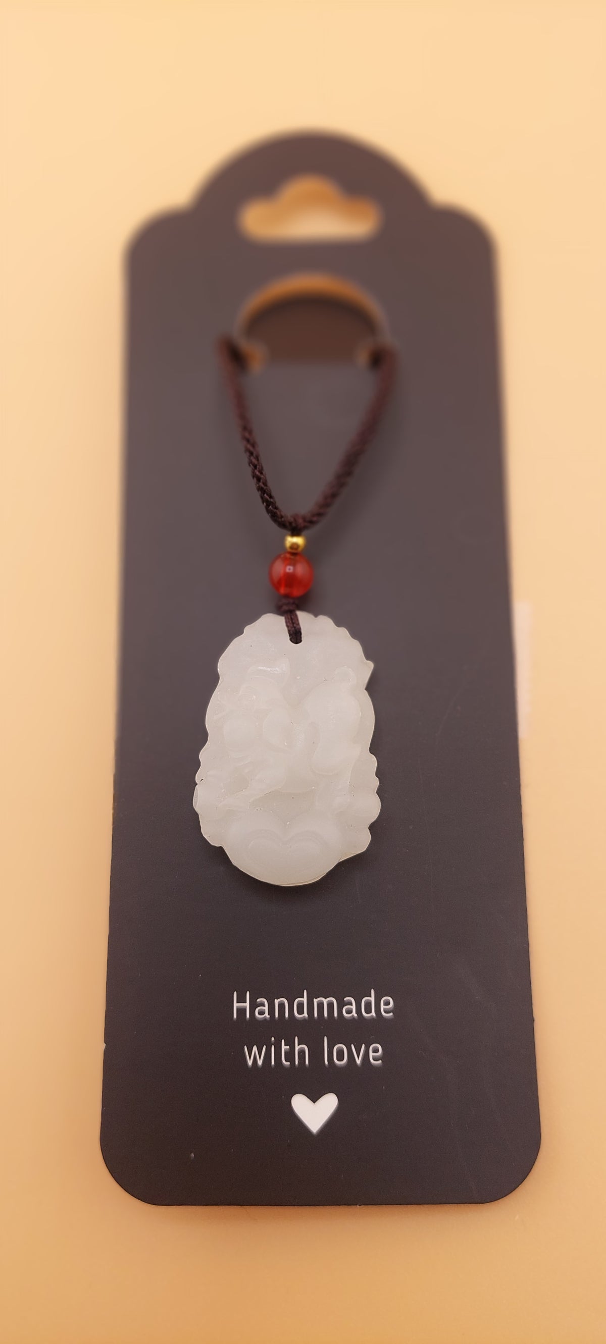 A white jade necklace with a rooster design, displayed on a brown card with the text 'Handmade with love'.
