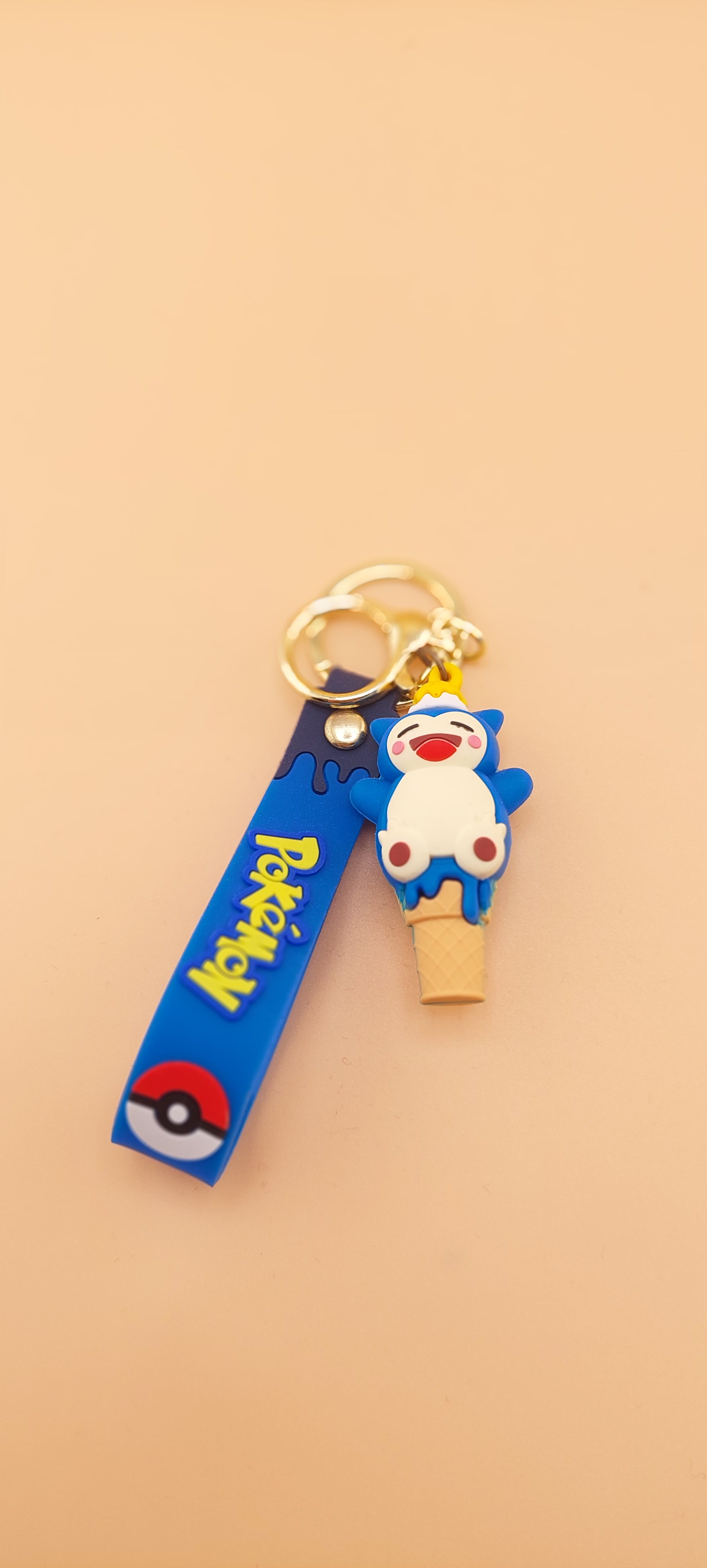 Two Pokemon keychains designed as ice cream cones with character toppings, placed against an orange background.