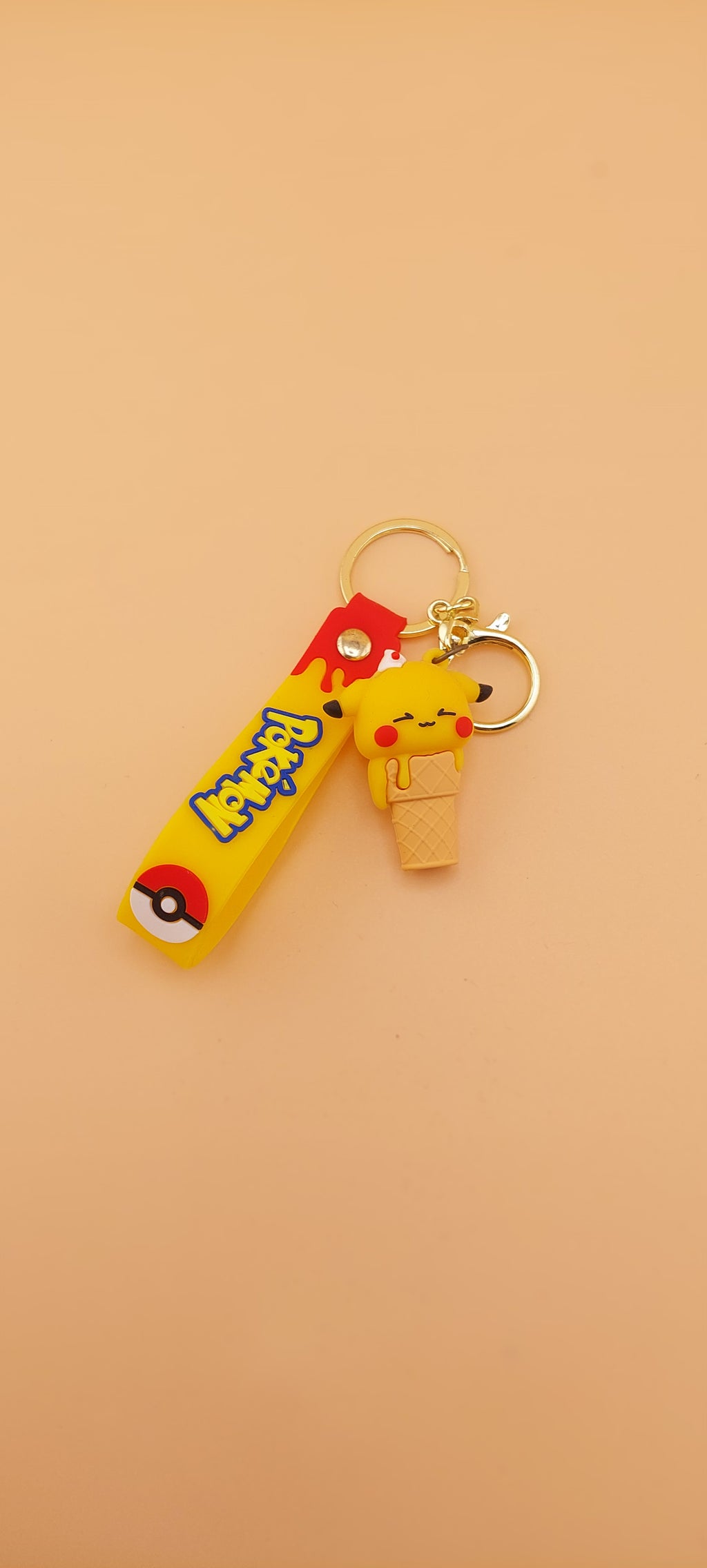 Two Pokemon keychains designed as ice cream cones with character toppings, placed against an orange background.