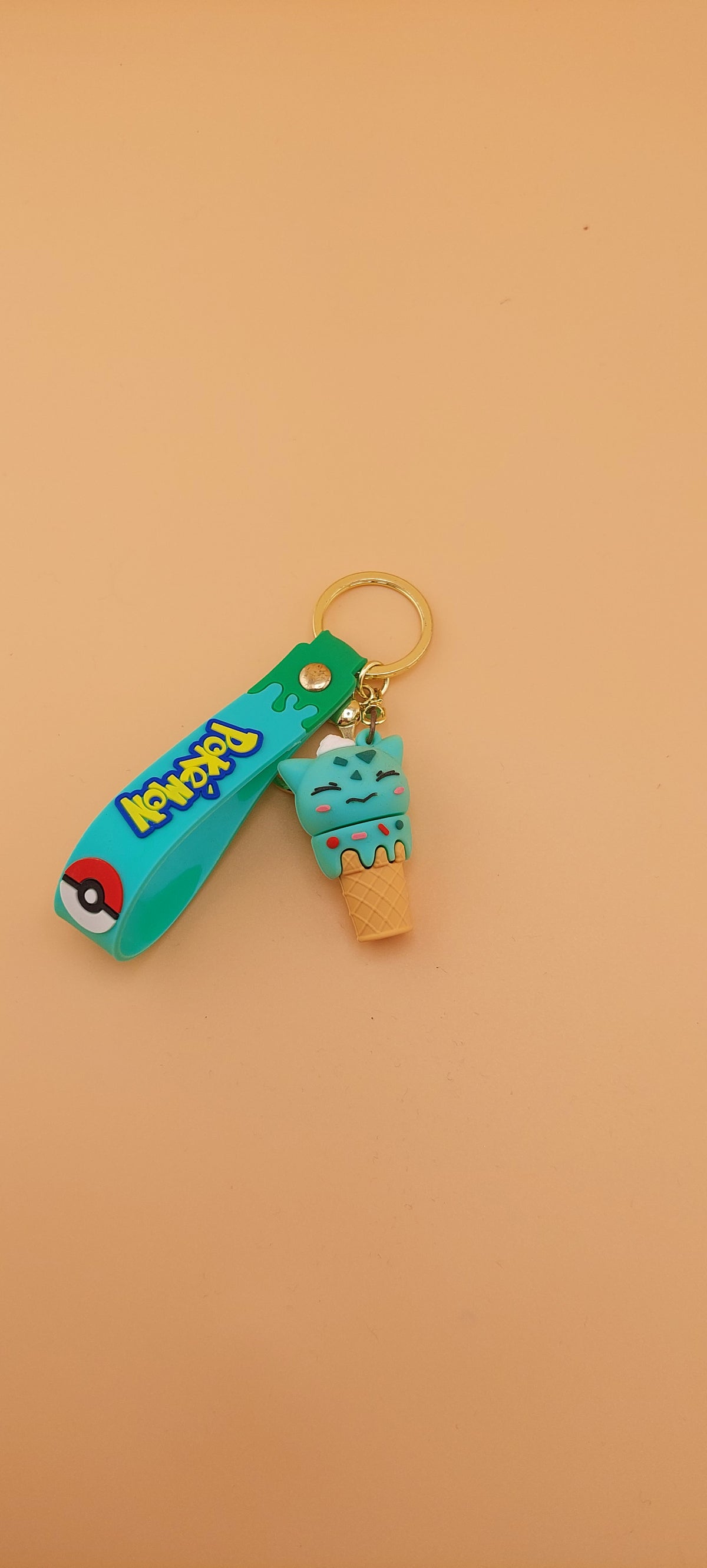 Two Pokemon keychains designed as ice cream cones with character toppings, placed against an orange background.
