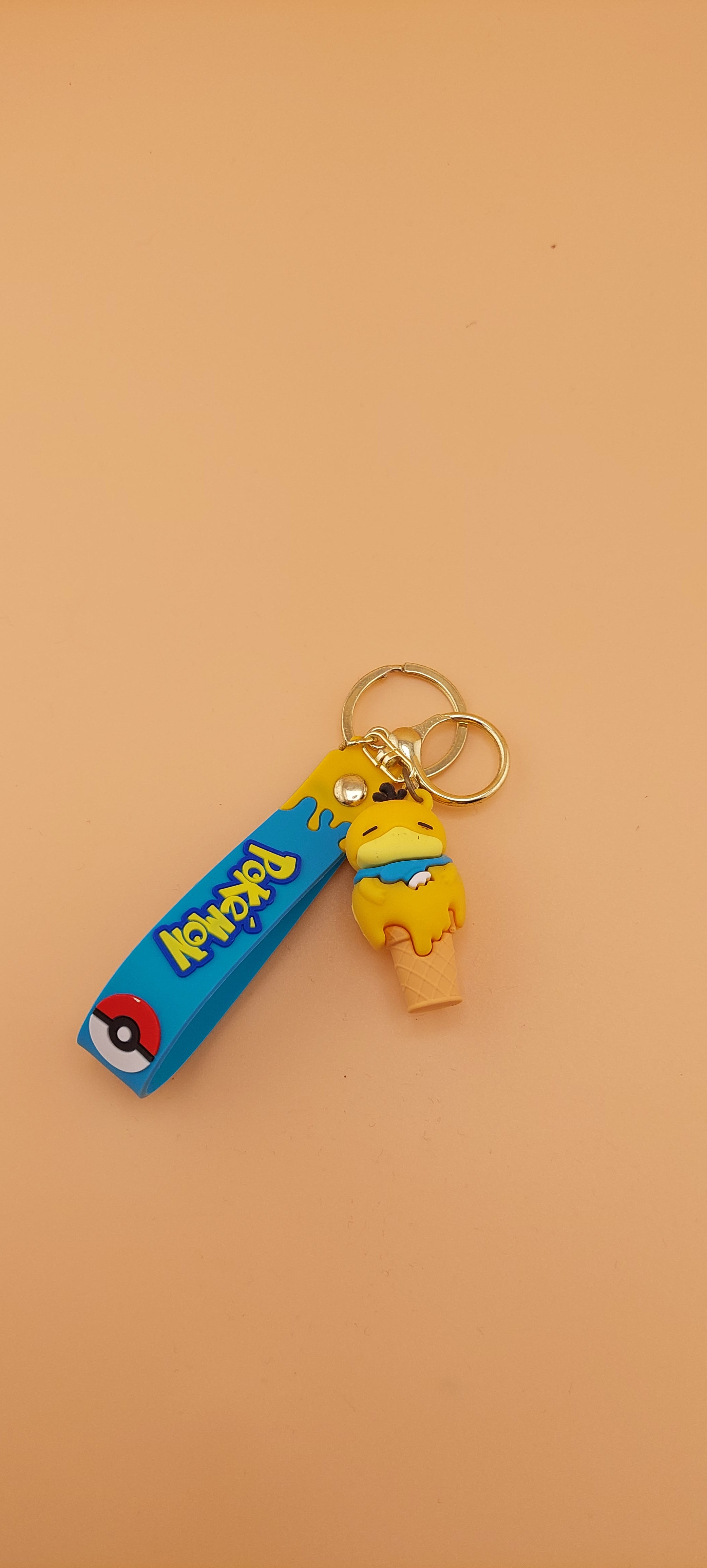Two Pokemon keychains designed as ice cream cones with character toppings, placed against an orange background.