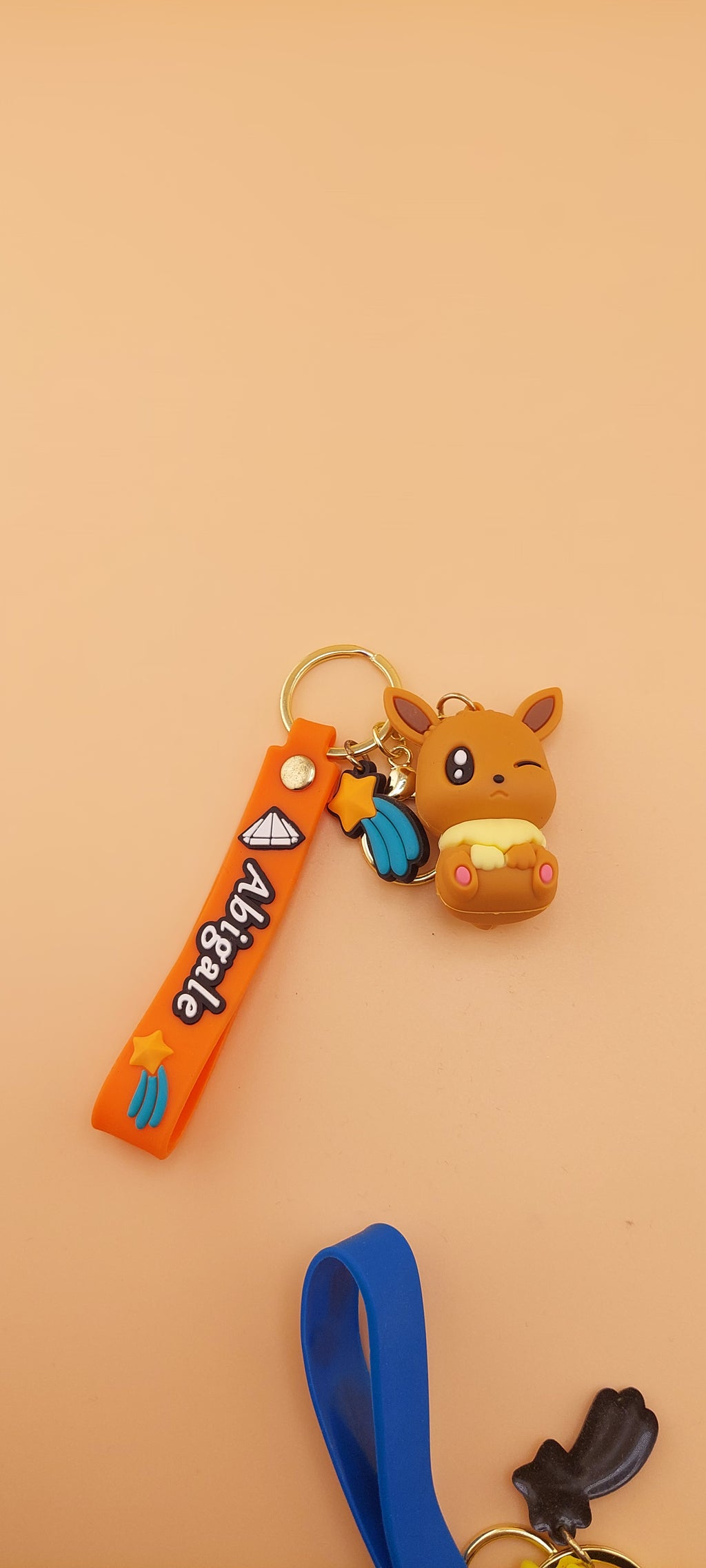A blue keychain featuring an animated character similar to Evee from the Pokemon franchise, displayed against a neutral background.
