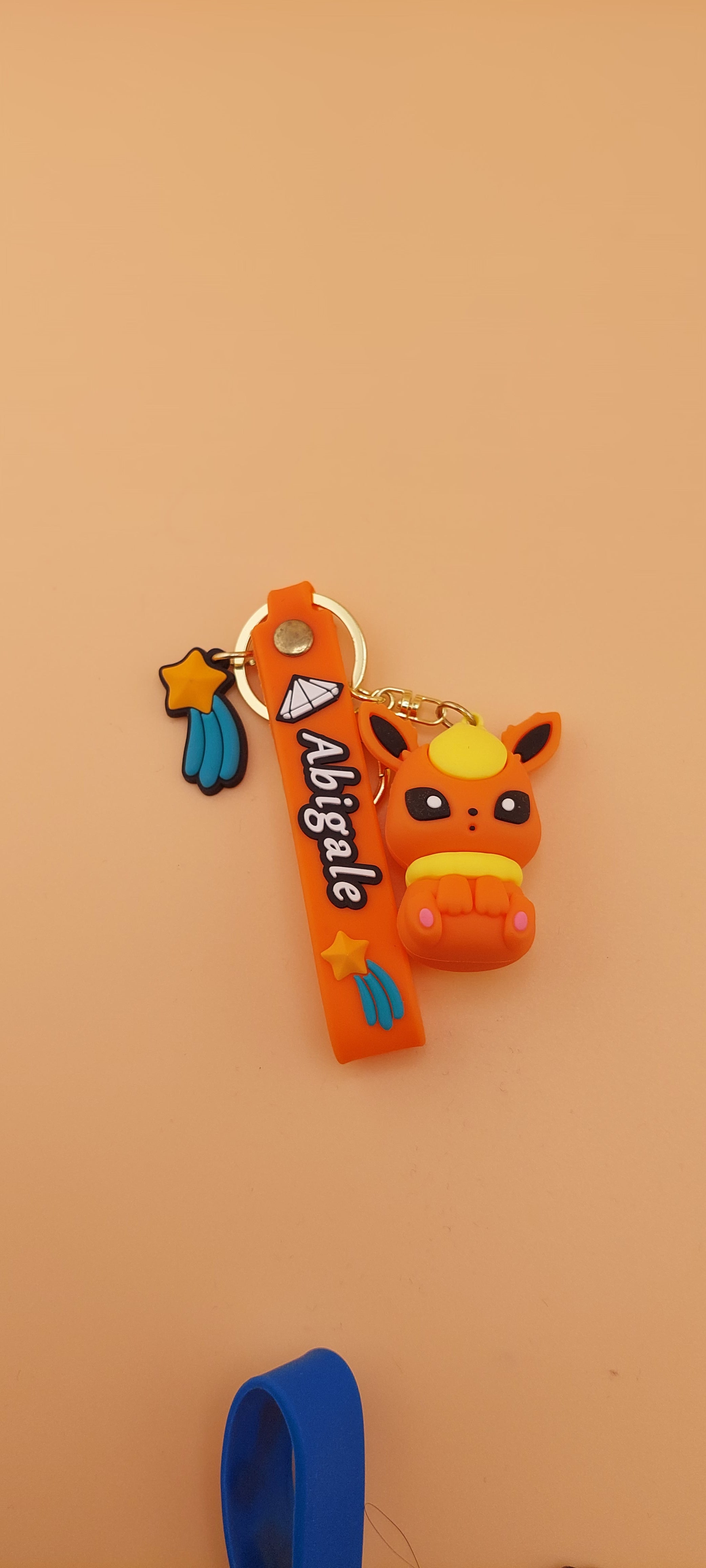 A blue keychain featuring an animated character similar to Evee from the Pokemon franchise, displayed against a neutral background.