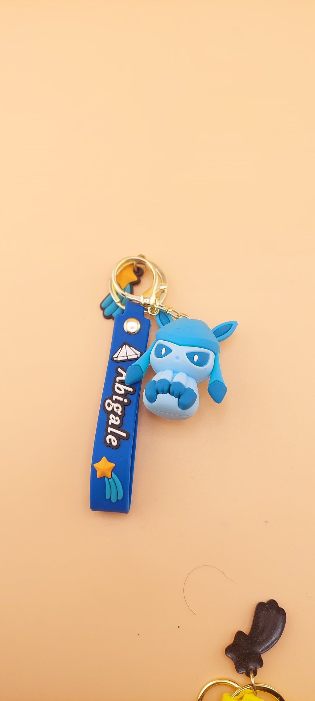A blue keychain featuring an animated character similar to Evee from the Pokemon franchise, displayed against a neutral background.