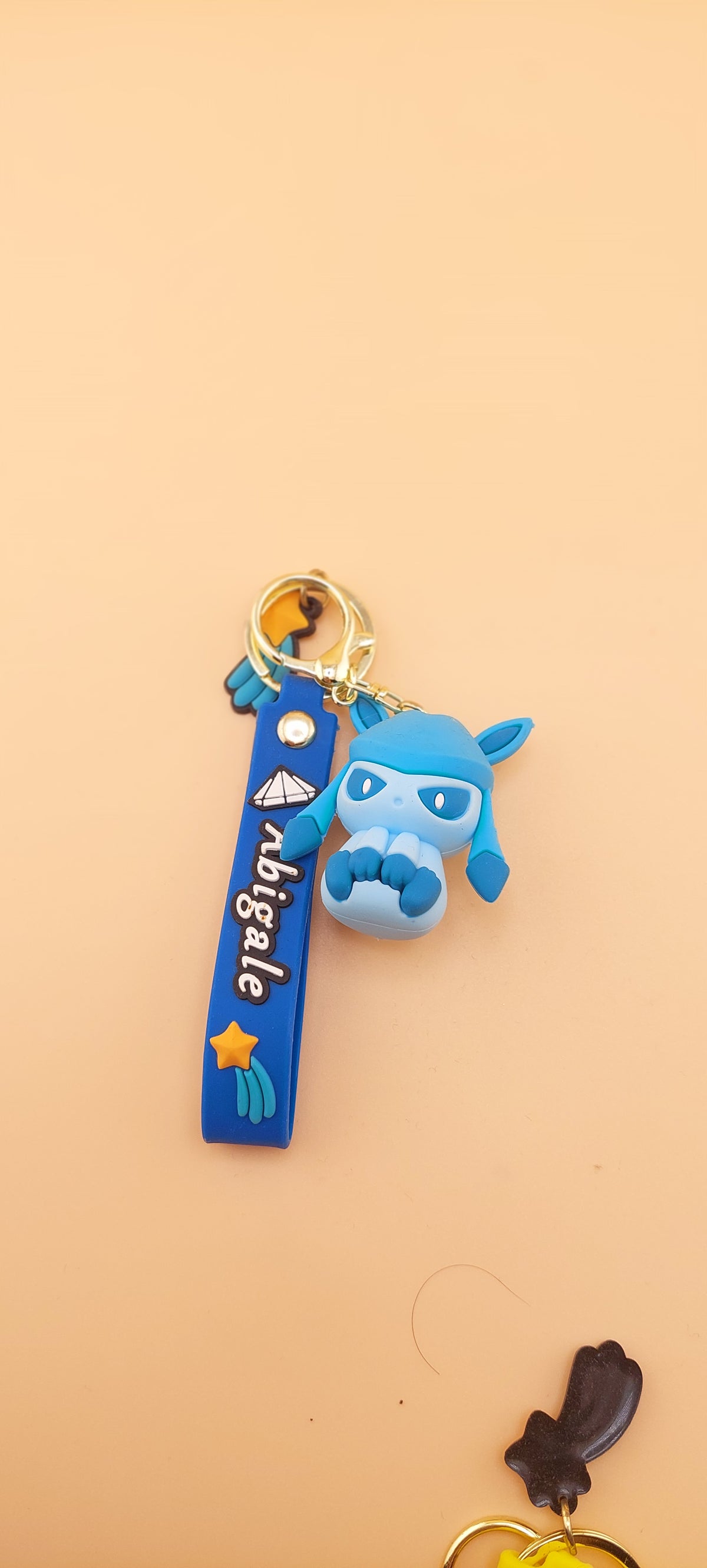A blue keychain featuring an animated character similar to Evee from the Pokemon franchise, displayed against a neutral background.