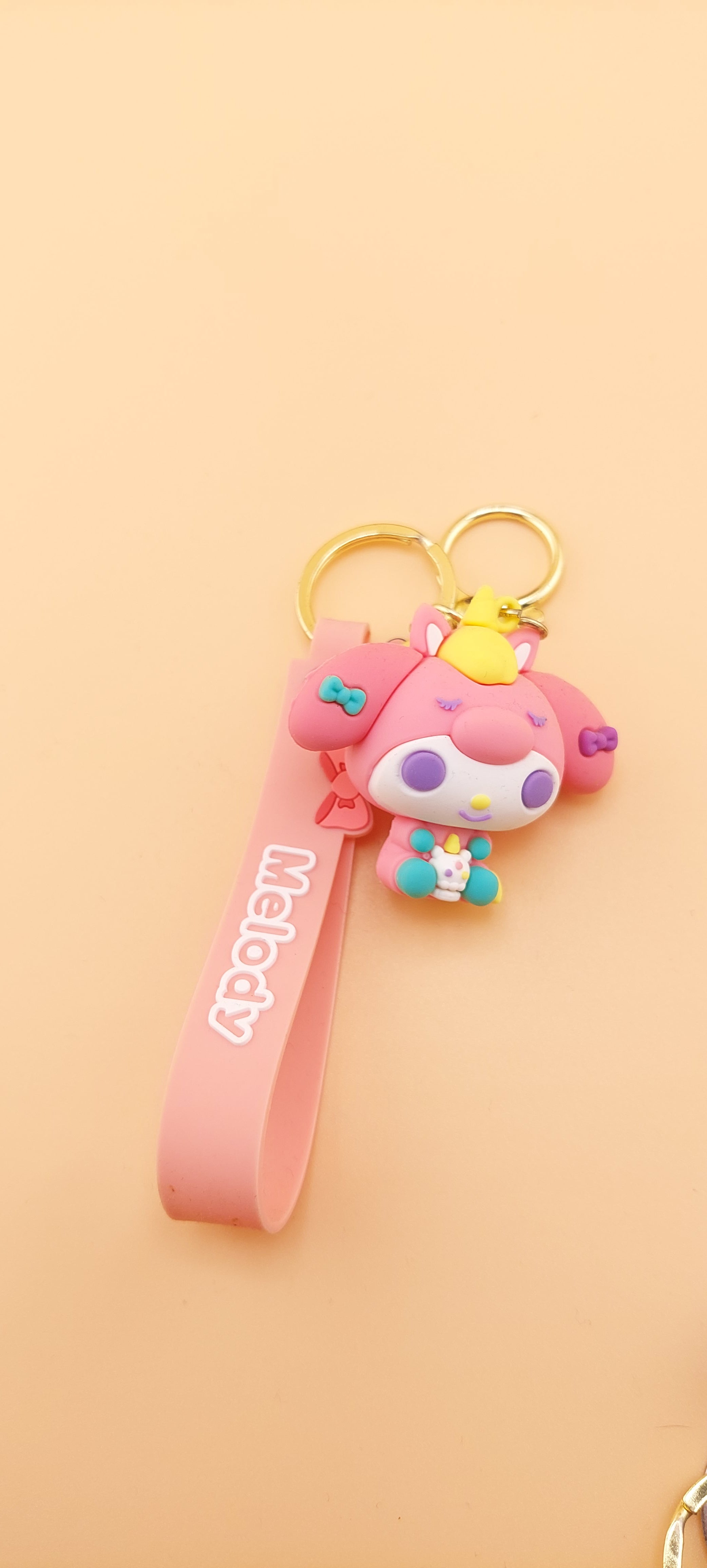 A pink keychain with a Hello Kitty theme, featuring a character illustration and text.