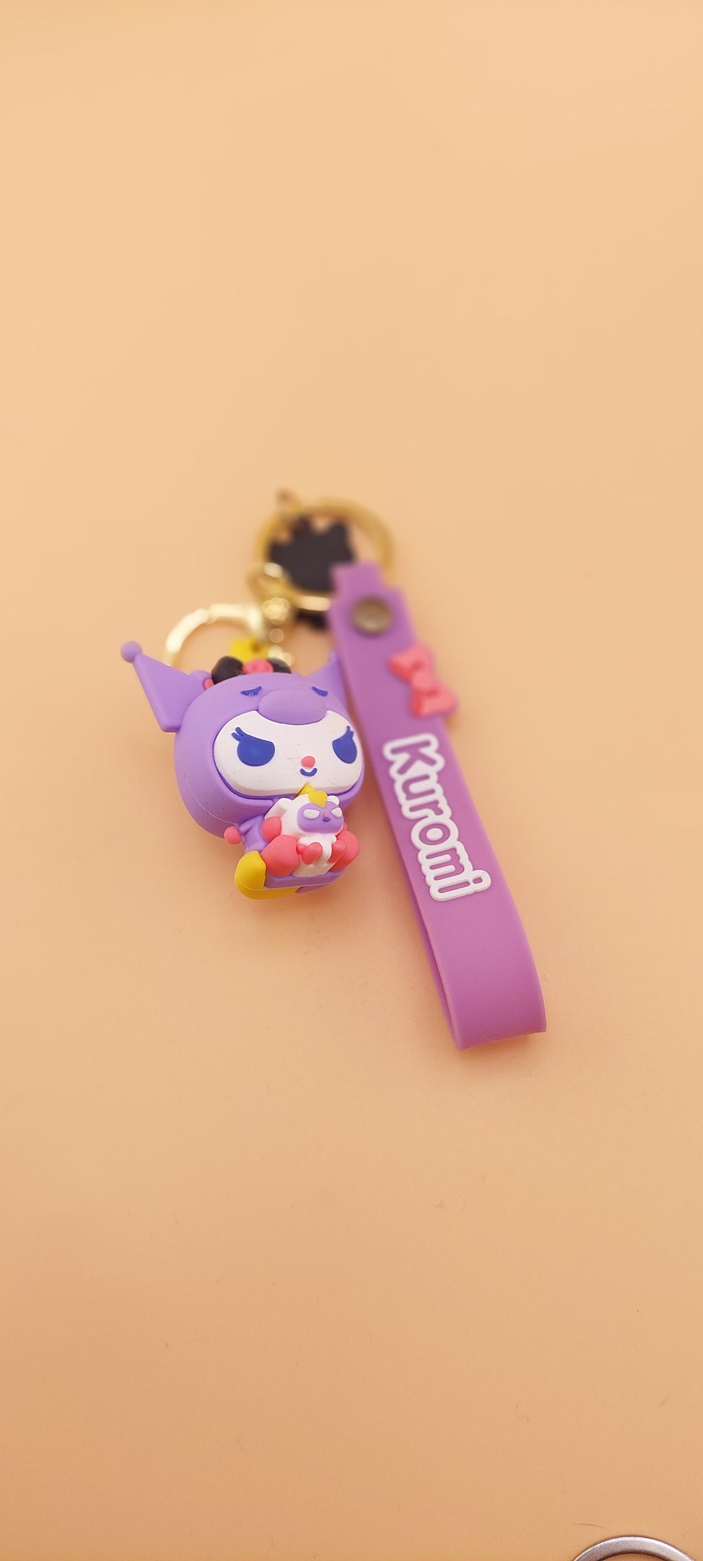 A pink keychain with a Hello Kitty theme, featuring a character illustration and text.