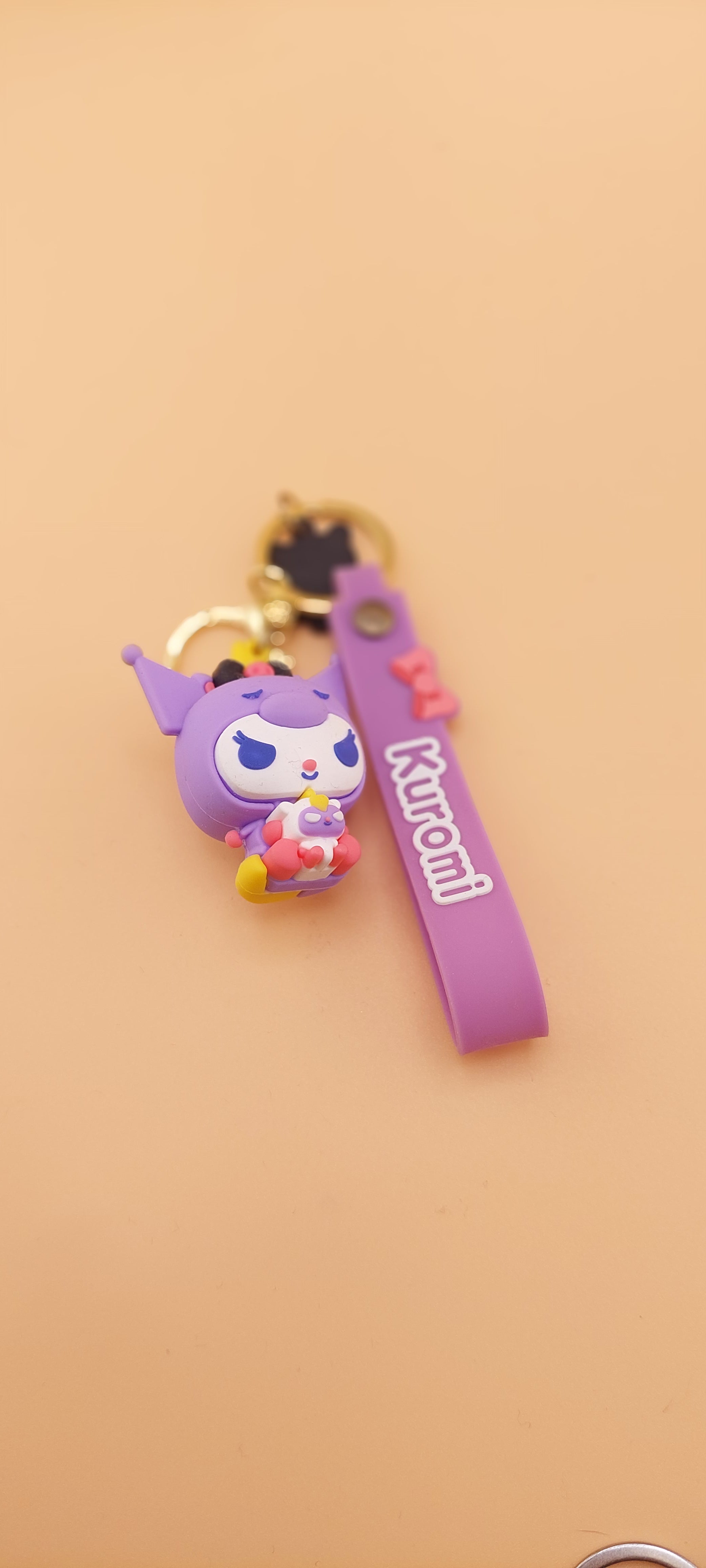 A pink keychain with a Hello Kitty theme, featuring a character illustration and text.