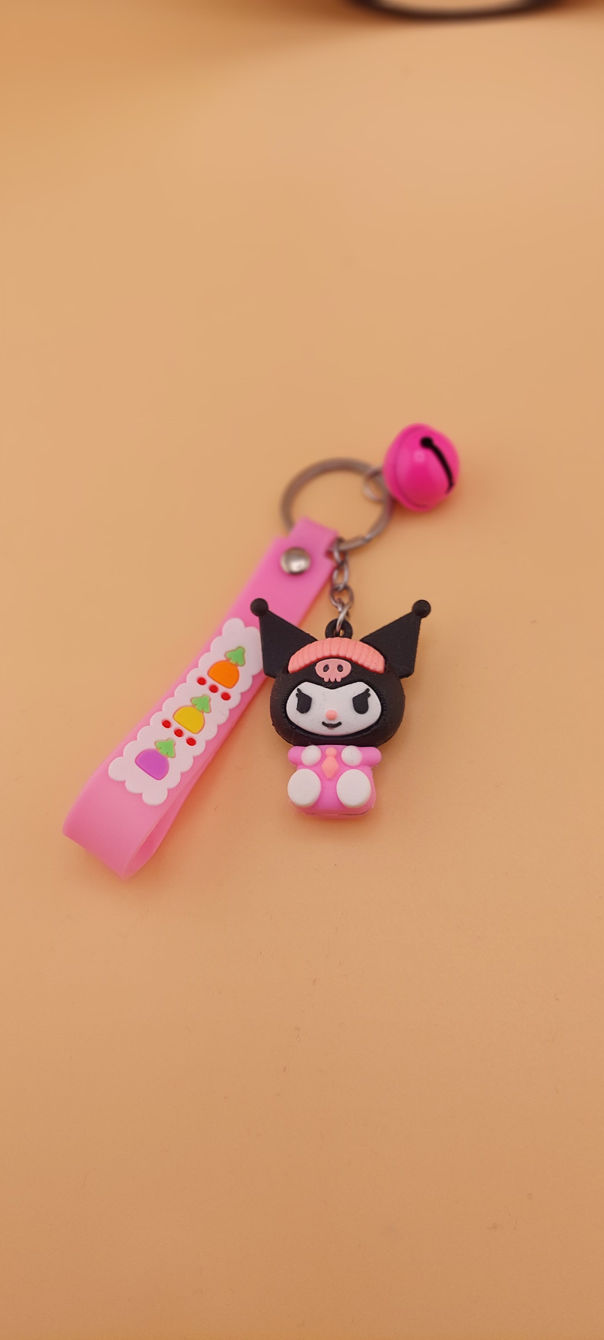 A pink keychain with a Hello Kitty theme, featuring a character illustration and text.