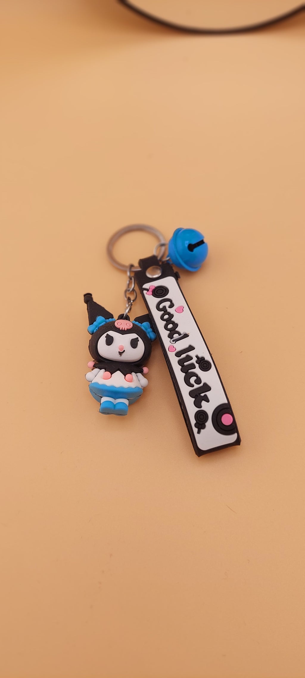 A pink keychain with a Hello Kitty theme, featuring a character illustration and text.