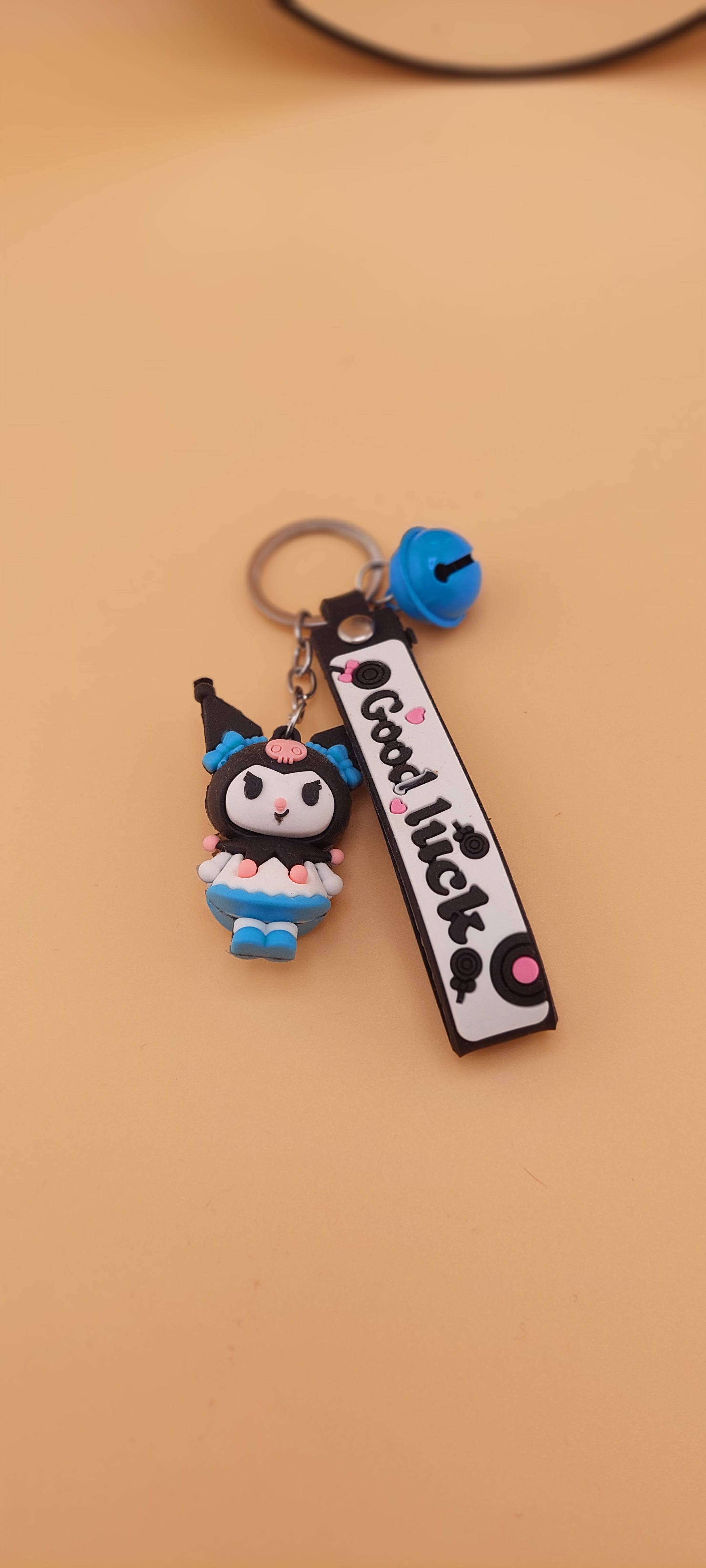 A pink keychain with a Hello Kitty theme, featuring a character illustration and text.