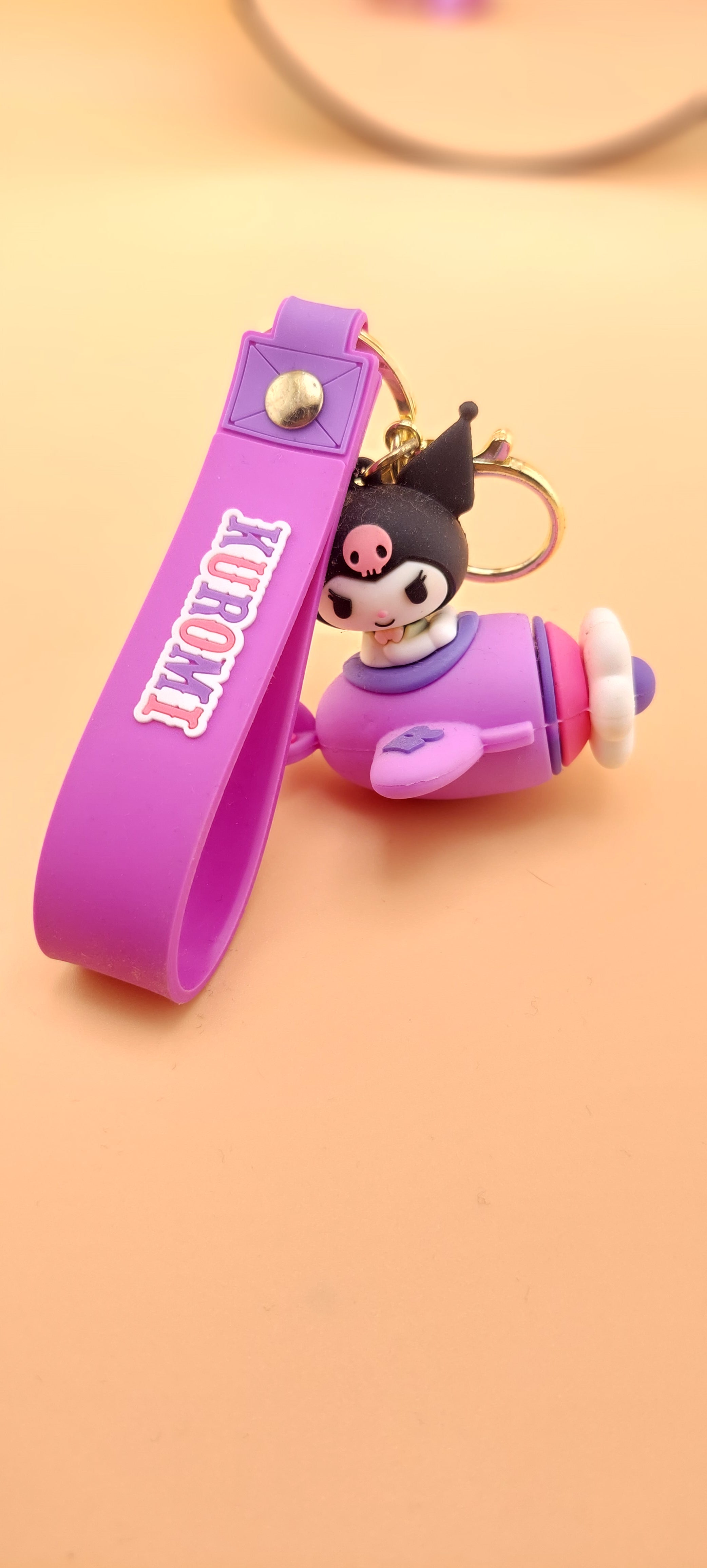 A pink keychain with a Hello Kitty theme, featuring a character illustration and text.