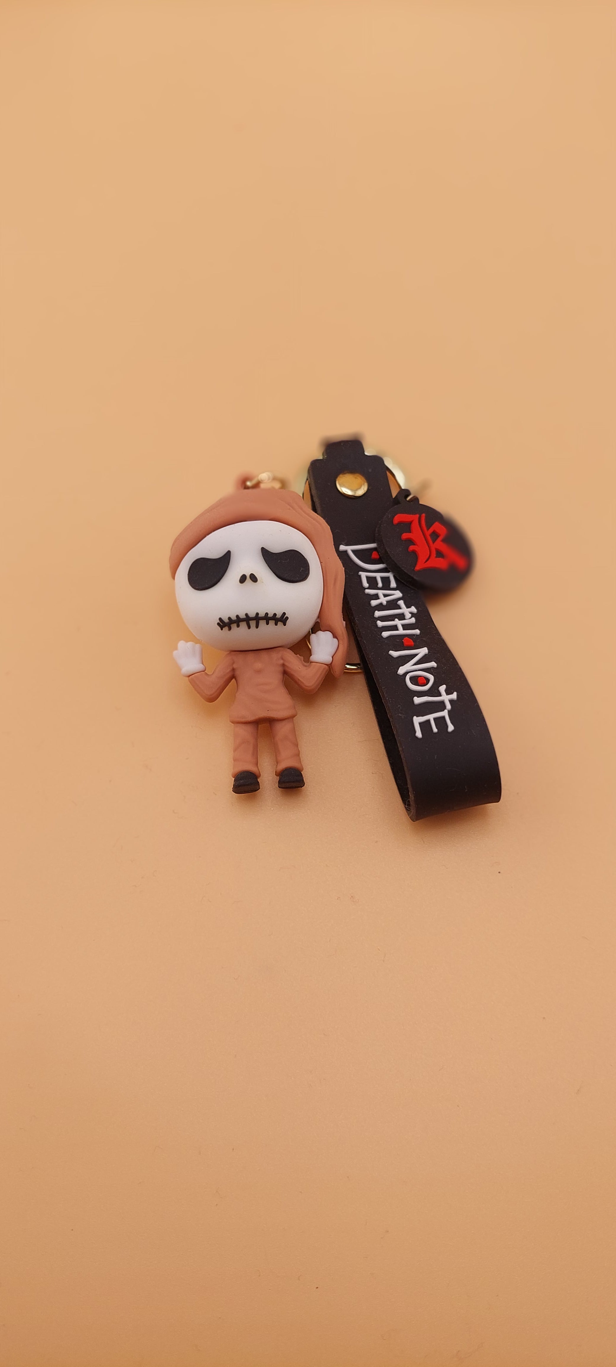 A keychain featuring an animated character from 'The Nightmare Before Christmas' attached to a brown strap with the text 'DEATH NOTE'.