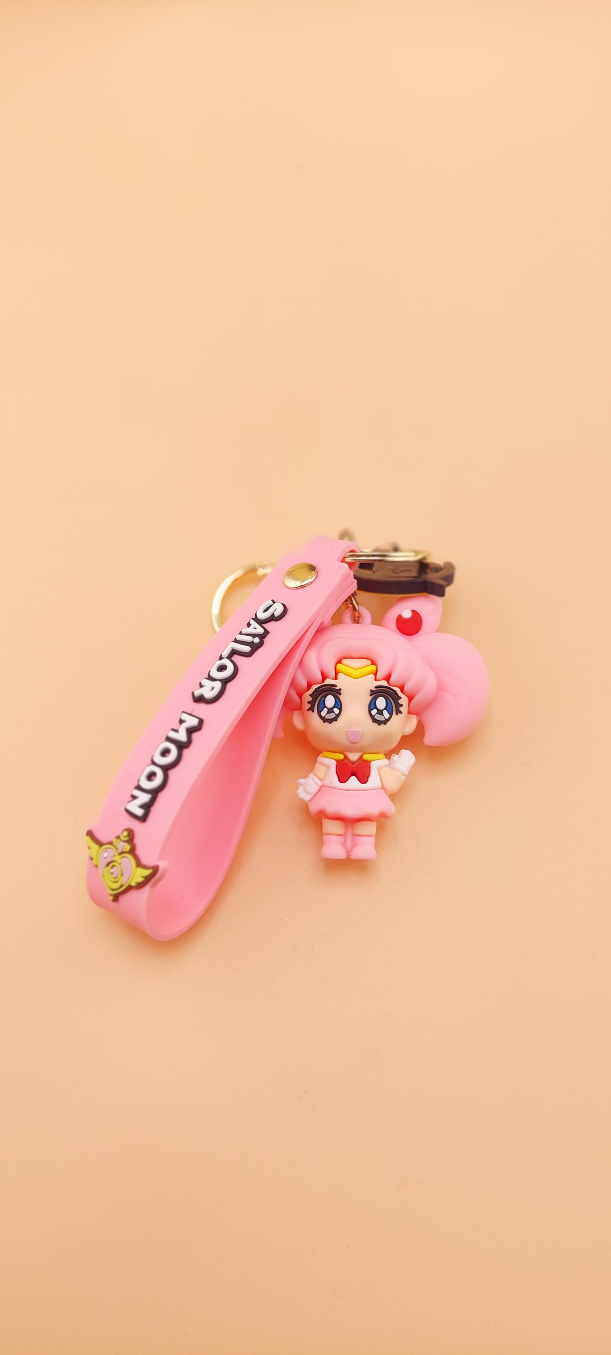 A pink-colored keychain featuring an anime character in a sailor outfit, set against a plain background.
