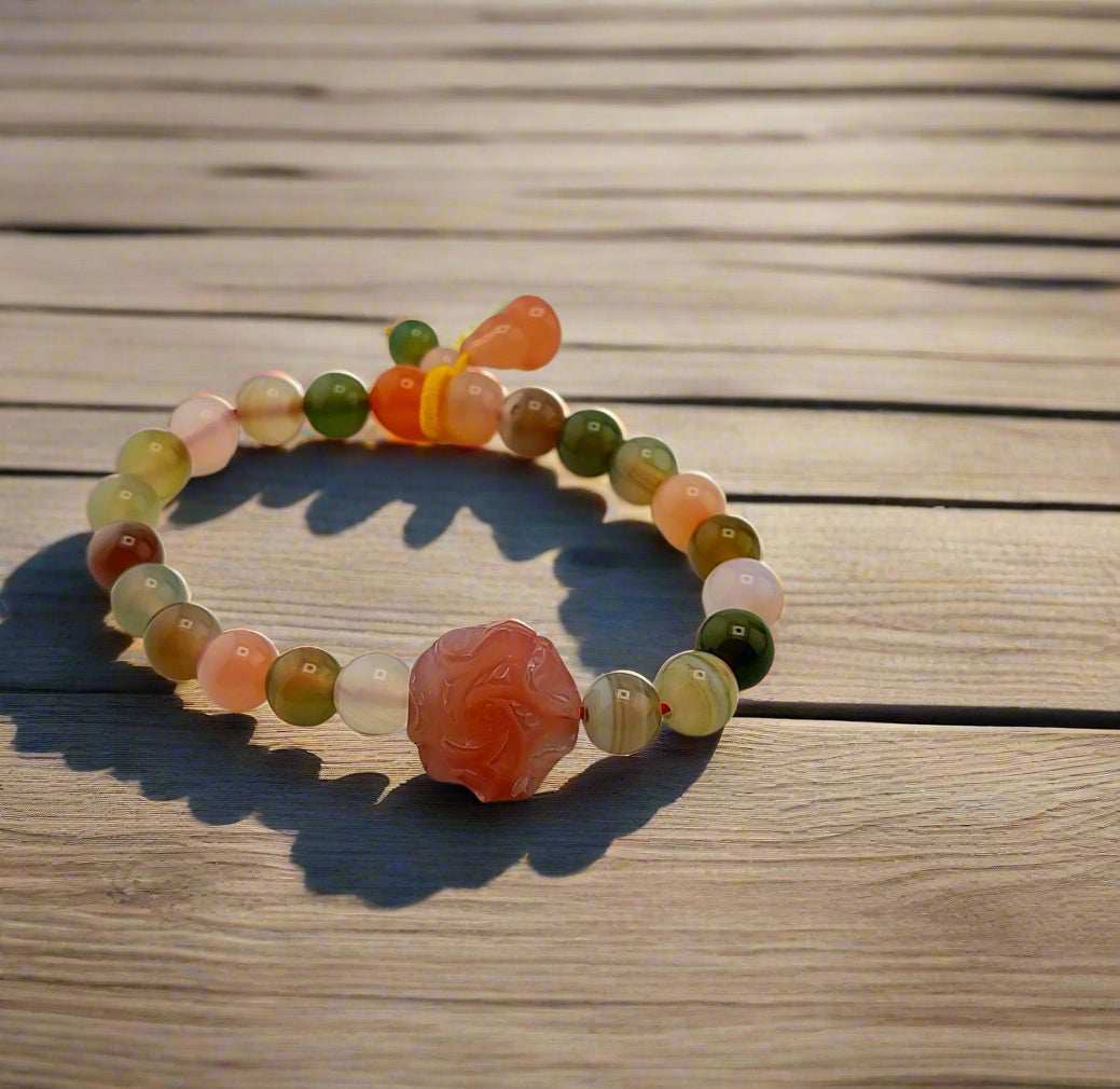 A multicolored agate rose bracelet laid out on wooden surface.