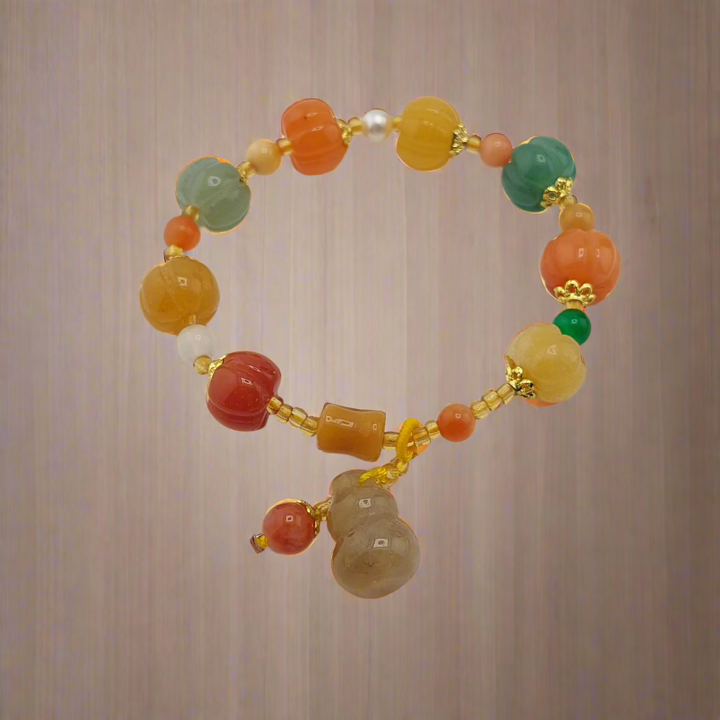 A multicolored bracelet with round and teardrop-shaped beads in shades of orange, green, and yellow, accented with gold-colored beads, displayed against a wooden background.