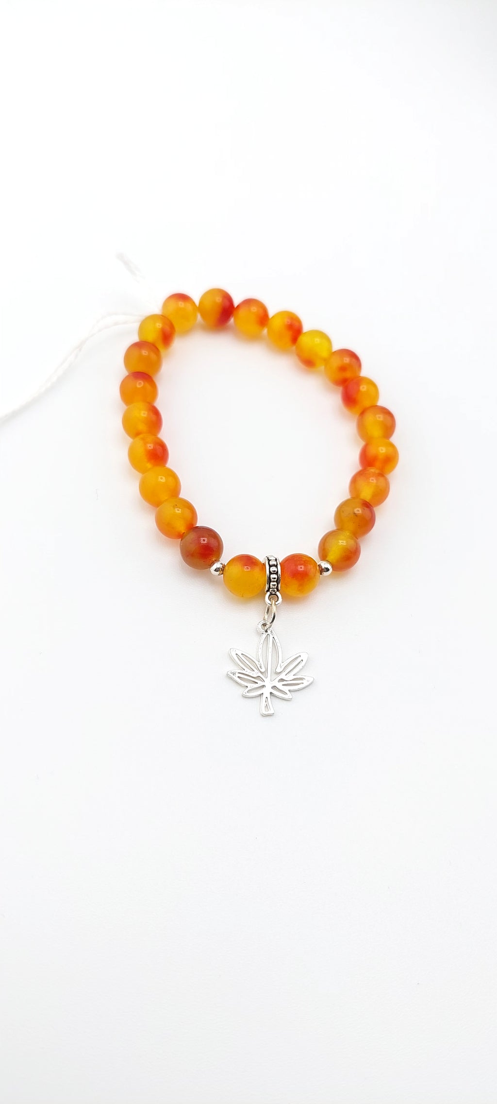 Beaded bracelet with a silver leaf charm on a white background