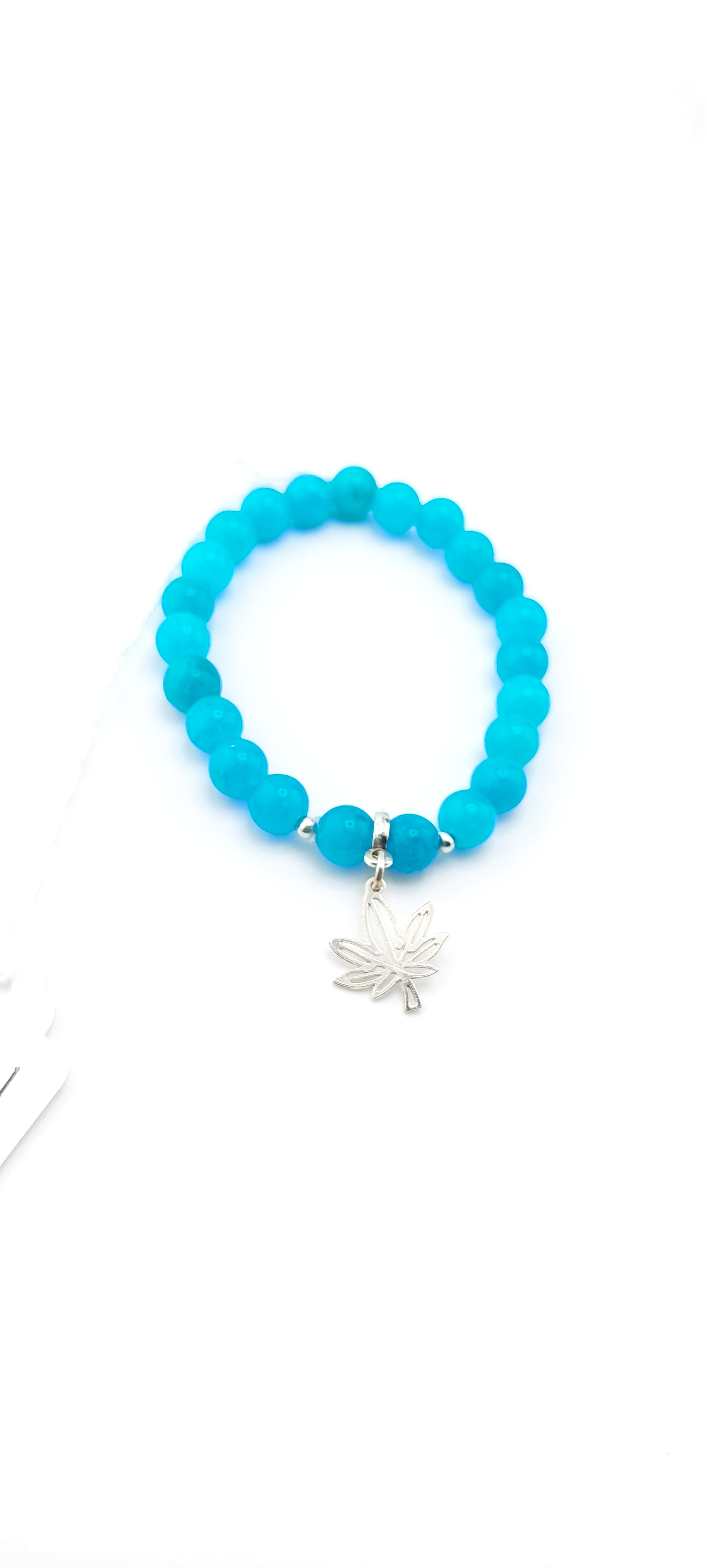 Turquoise beaded bracelet with a silver charm on a white background
