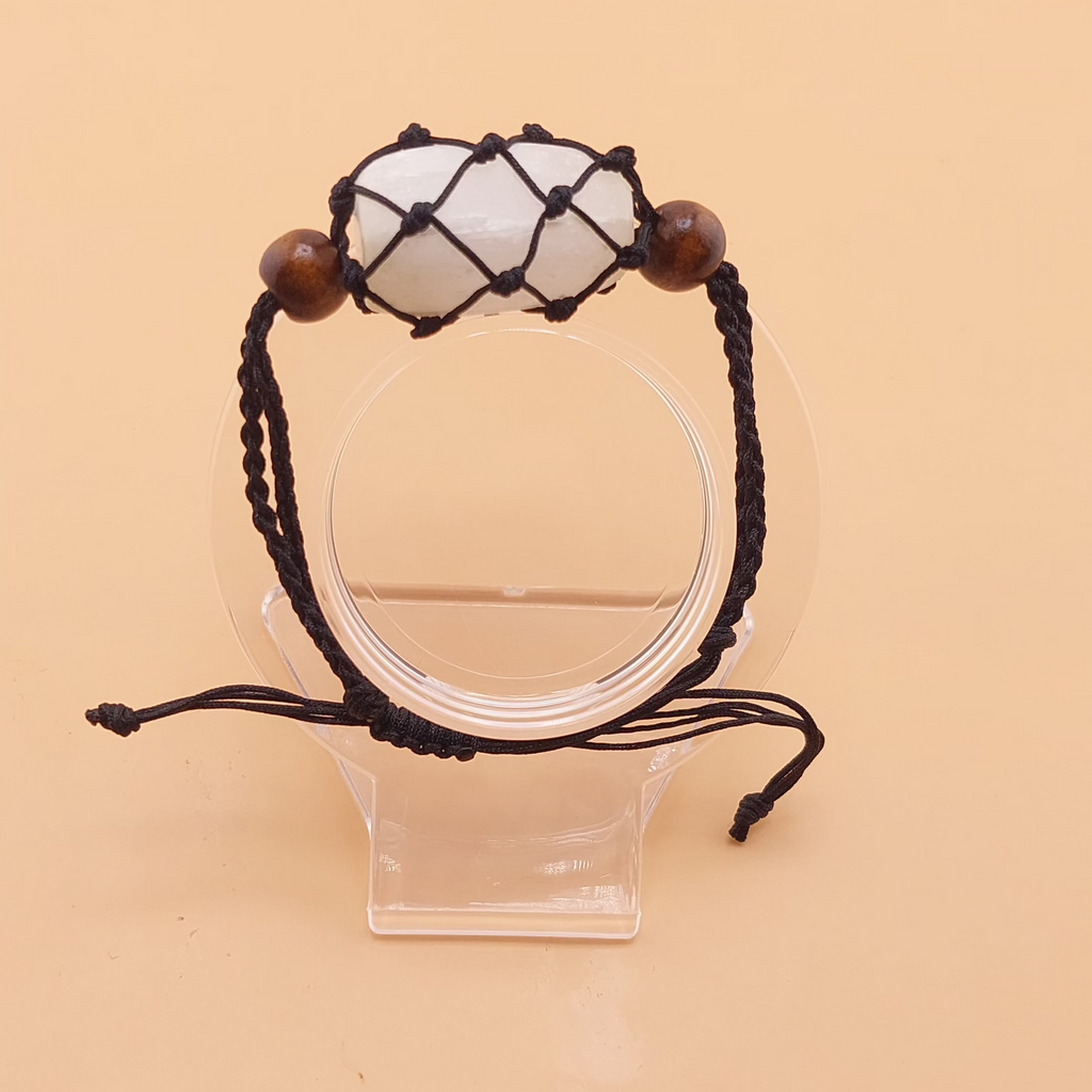 A brown Macrame selenite tumbled stone bracelet displayed on a clear stand against a beige background.