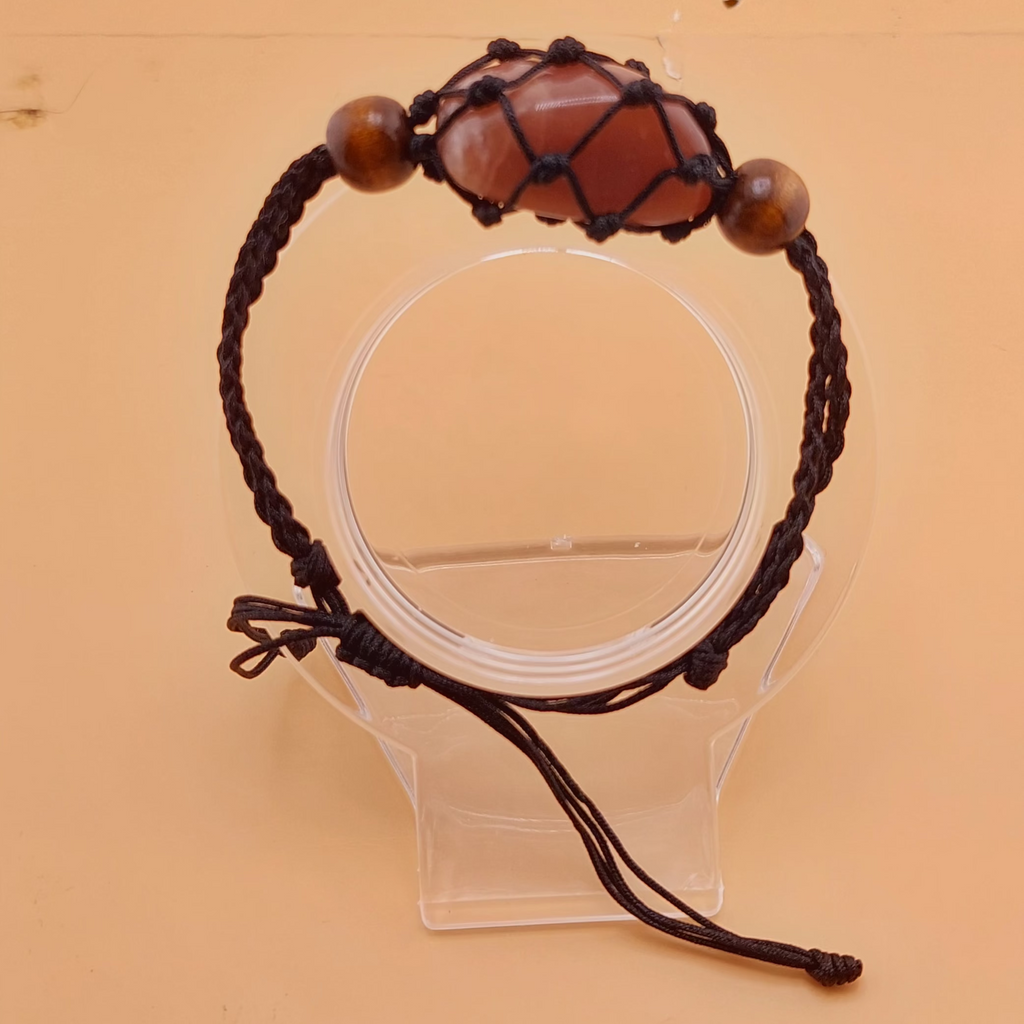 A brown Macrame tumbled stone bracelet displayed on a clear stand against a beige background.