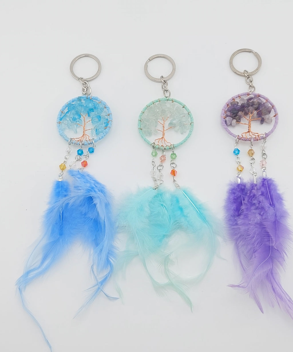 A set of three dream catcher keychains with stone crystal chips and decorative tree of life designs, featuring blue, white, and purple feathers.