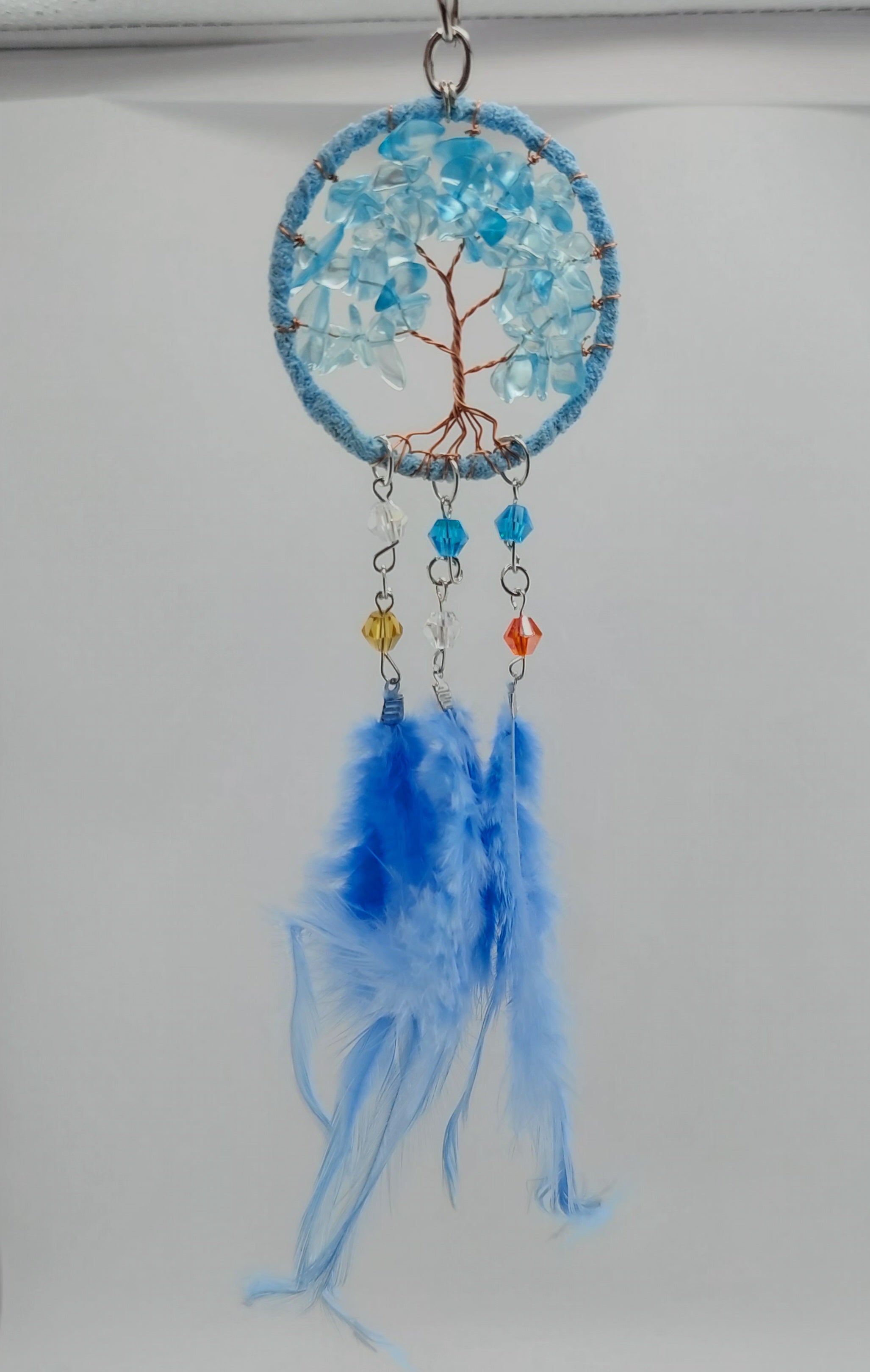A set of three dream catcher keychains with stone crystal chips and decorative tree of life designs, featuring blue, white, and purple feathers.