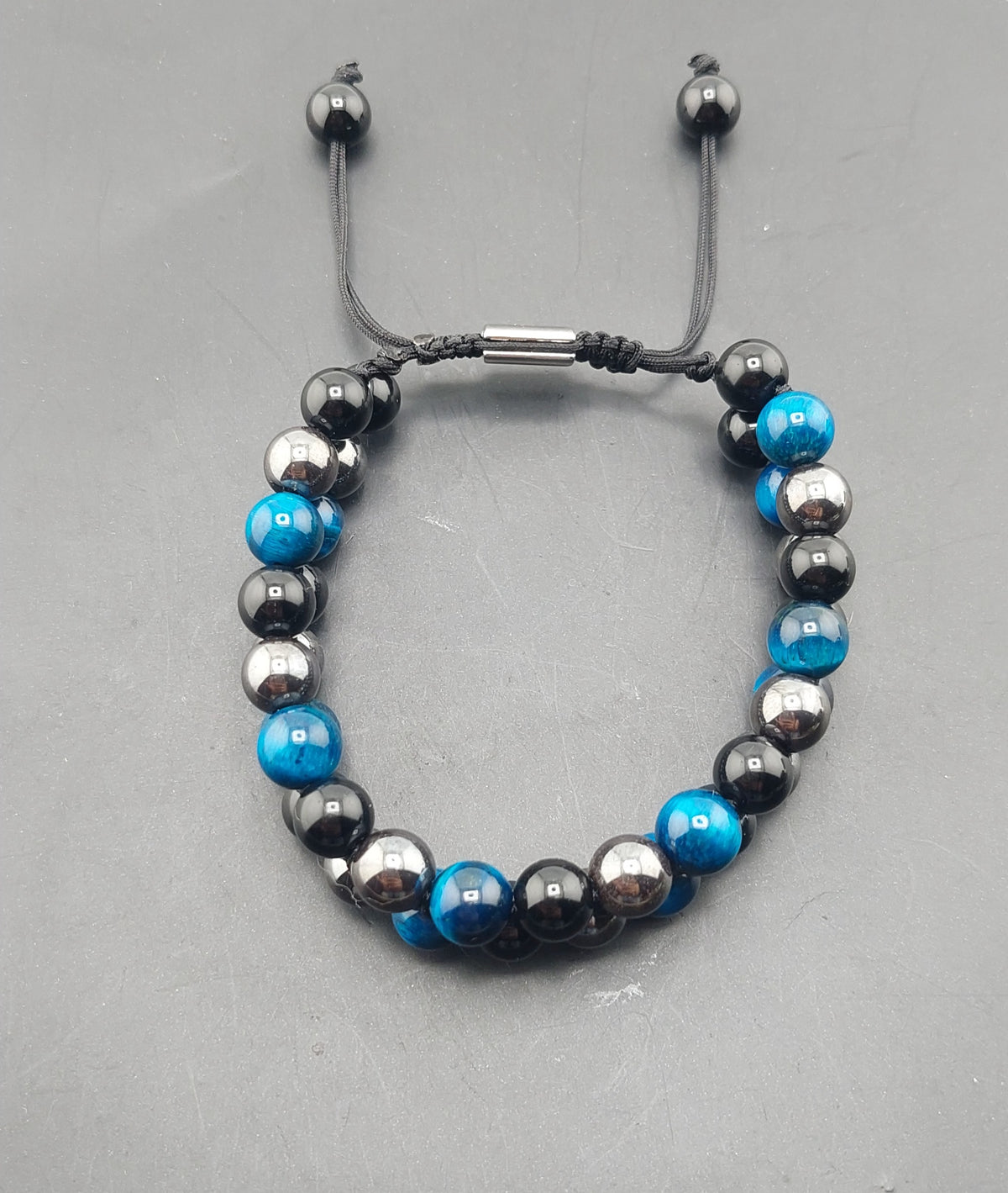 A men's macrame bracelet with blue and black beads, featuring an adjustable closure.