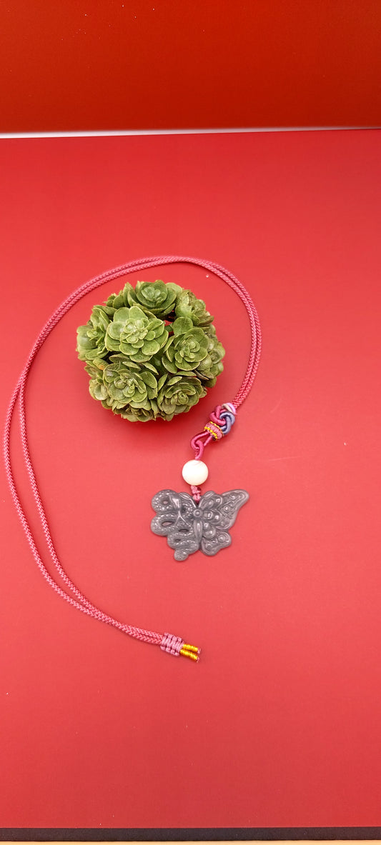A blue water jade necklace with a snake and butterfly design, displayed against a red background.