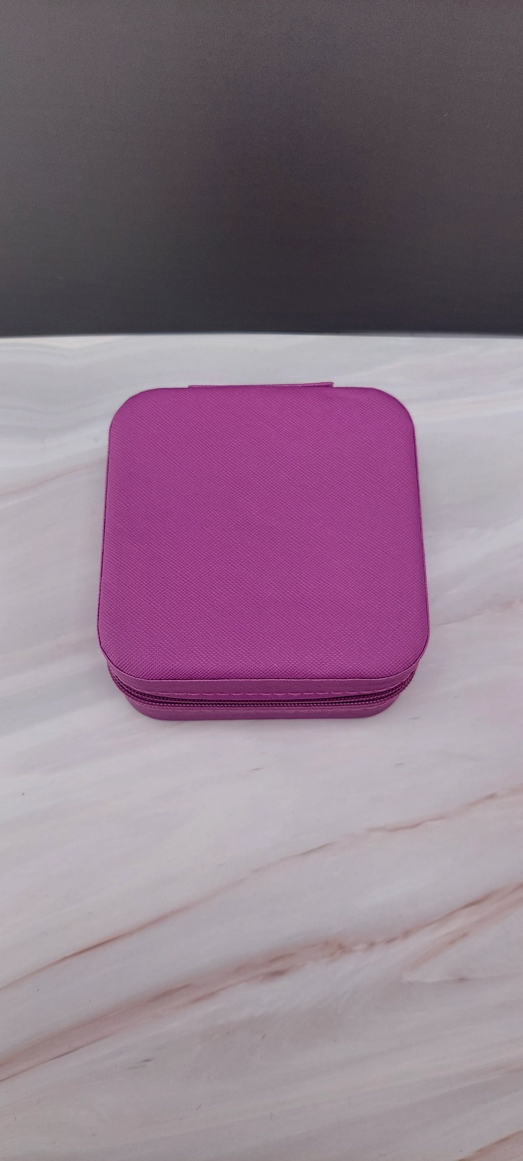A square jewelry box made of  purple material with a beige interior, featuring compartments for organizing jewelry.